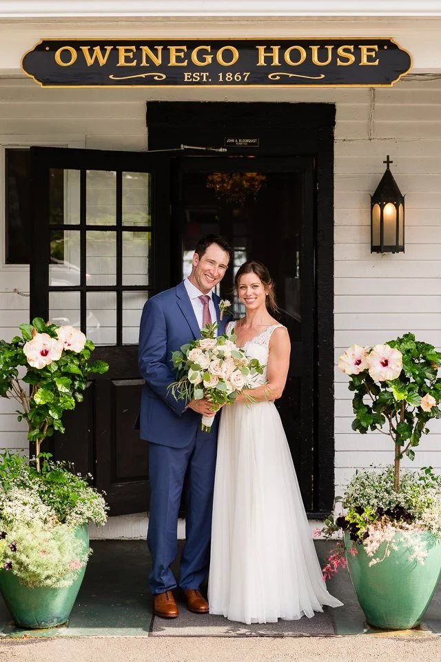 02-couple-wedding-attire-stand-smiling-entrance.jpg