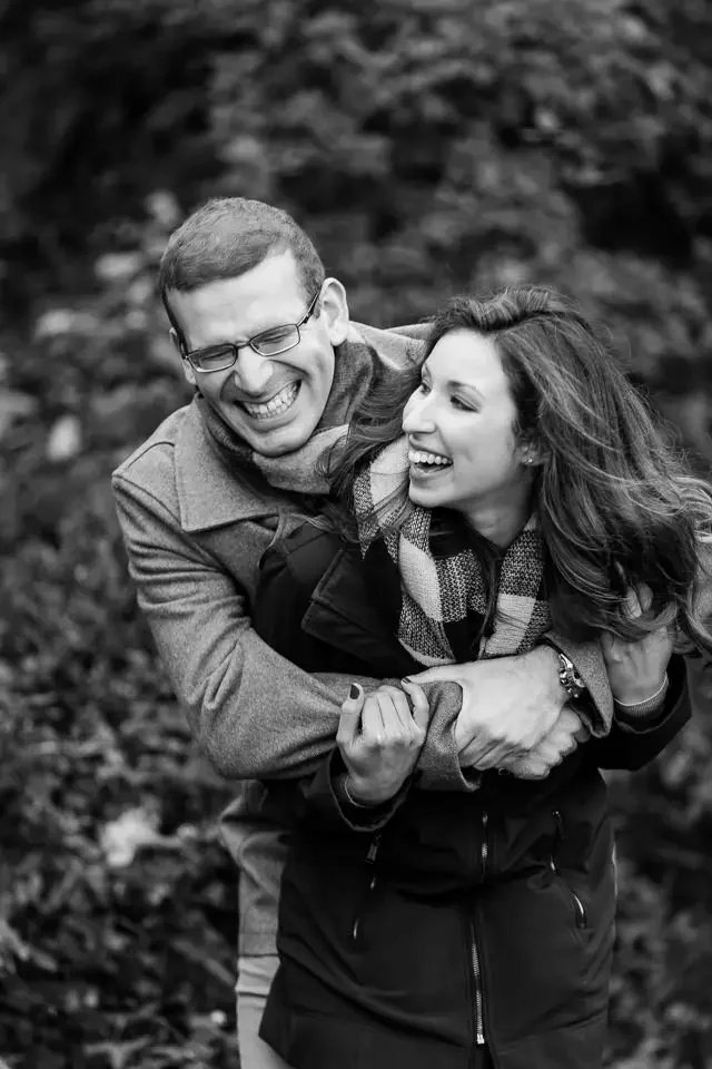 Couple laughing and embracing during a candid engagement session in Newport, captured in a natural, playful moment.