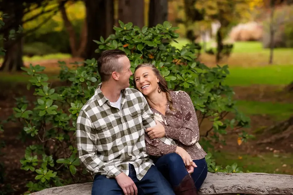 Engaged couple laughing together during a relaxed engagement session, captured in a candid moment that shows genuine connection and comfort in front of the camera.