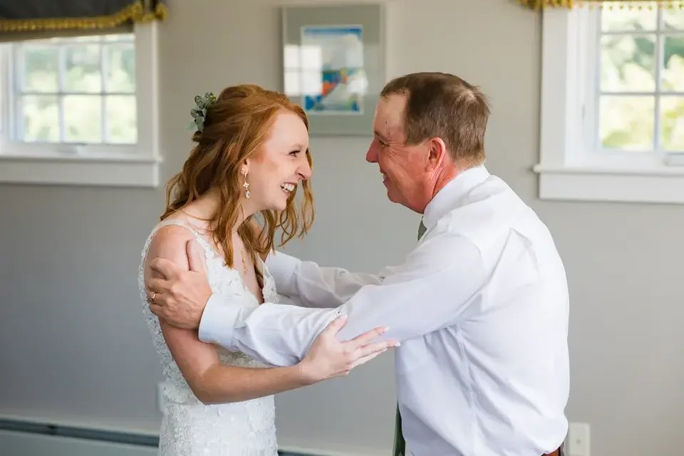 Bride shares an emotional first look with her father before the wedding ceremony, smiling and holding each other.