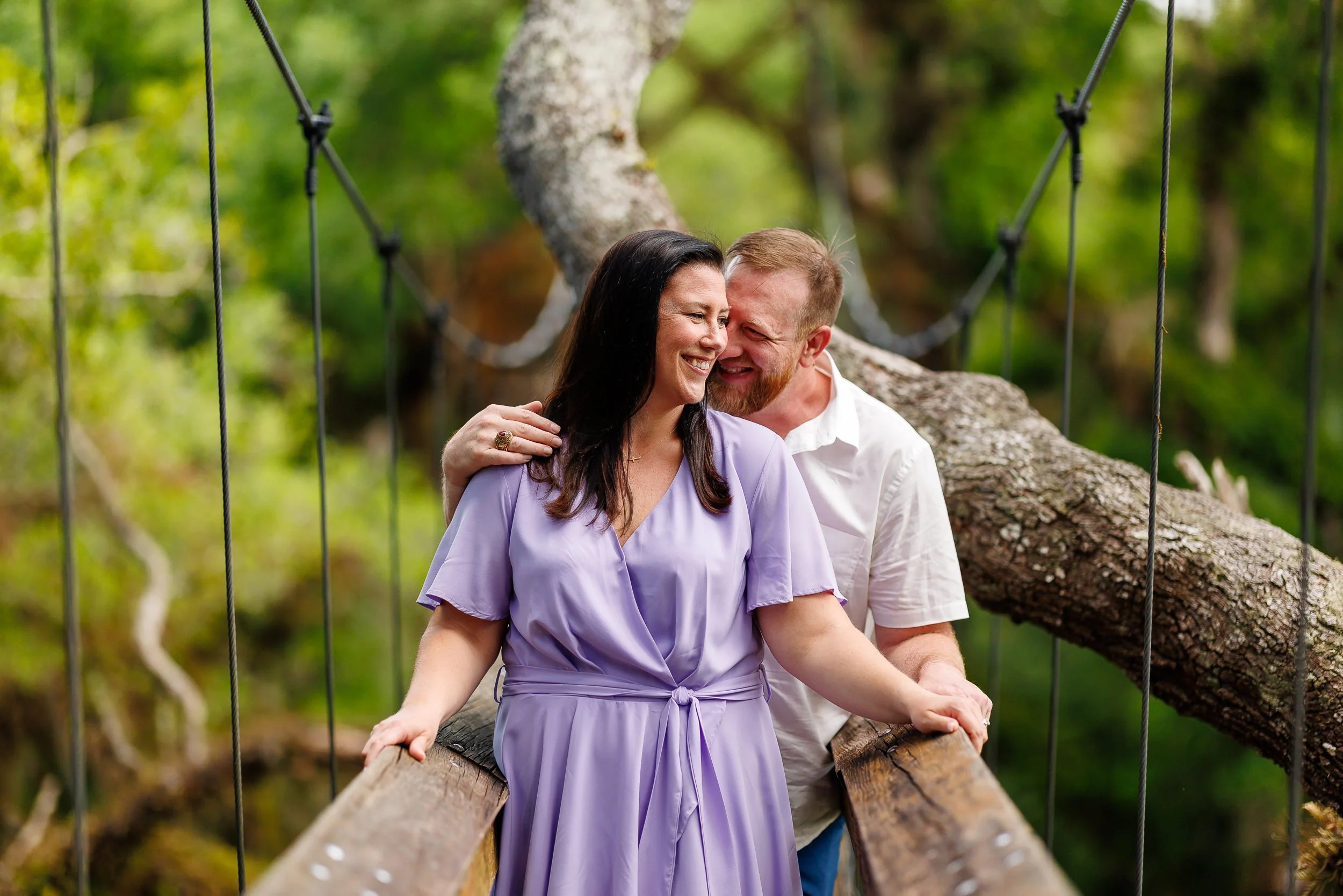 Erin leaning back into Will, both mid-laugh, framed by the suspension cables of the Myakka canopy walkway.