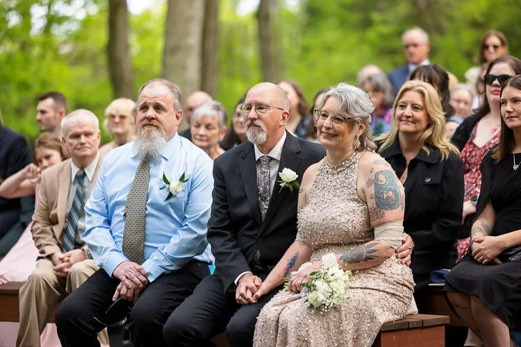 Parents seated together during the ceremony, sharing quiet smiles and emotional moments without digital distractions.