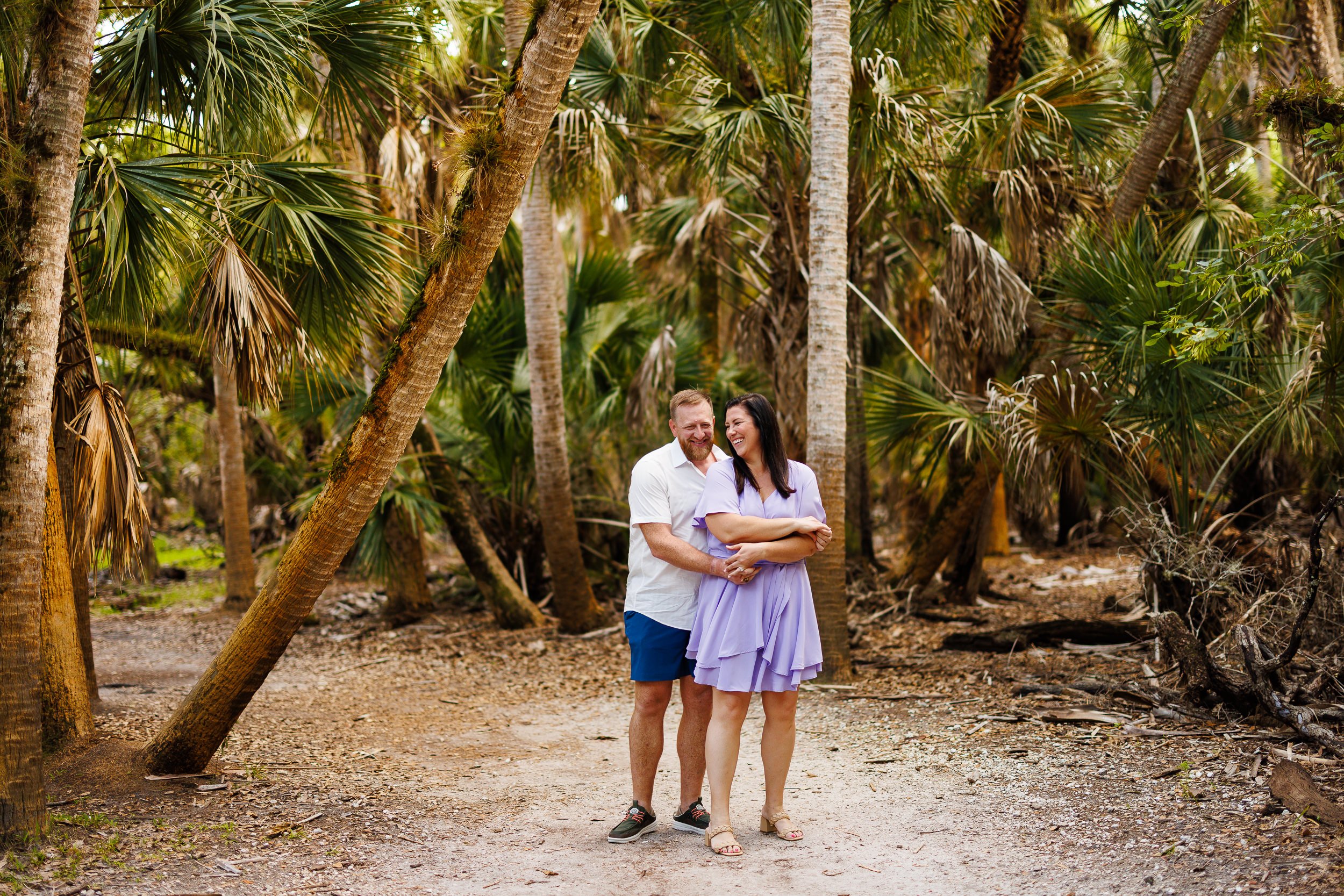 Will and Erin standing close together on the sandy trail at Myakka, palms and afternoon light behind them.