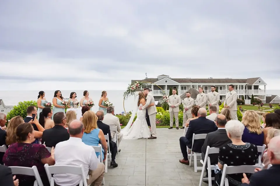 Wedding ceremony with guests fully present, seated and watching as the couple exchanges vows outdoors