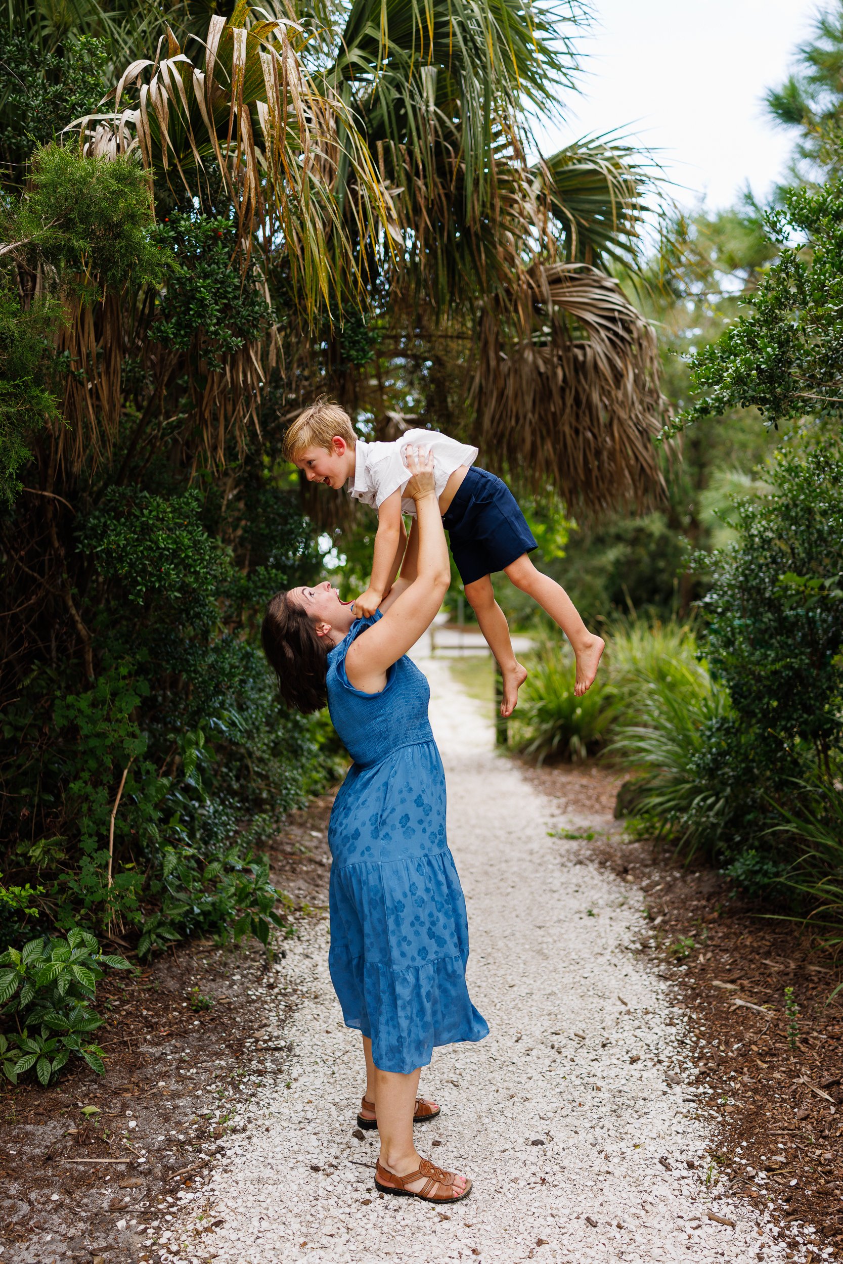 A parent lifting a child into the air on a gravel path at Phillippi Estate Park