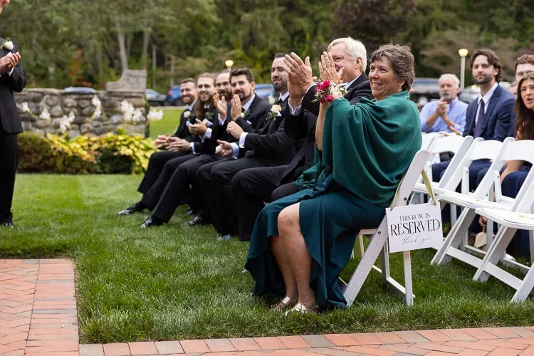 Guests applauding at the conclusion of a wedding ceremony, fully engaged and celebrating the couple together.