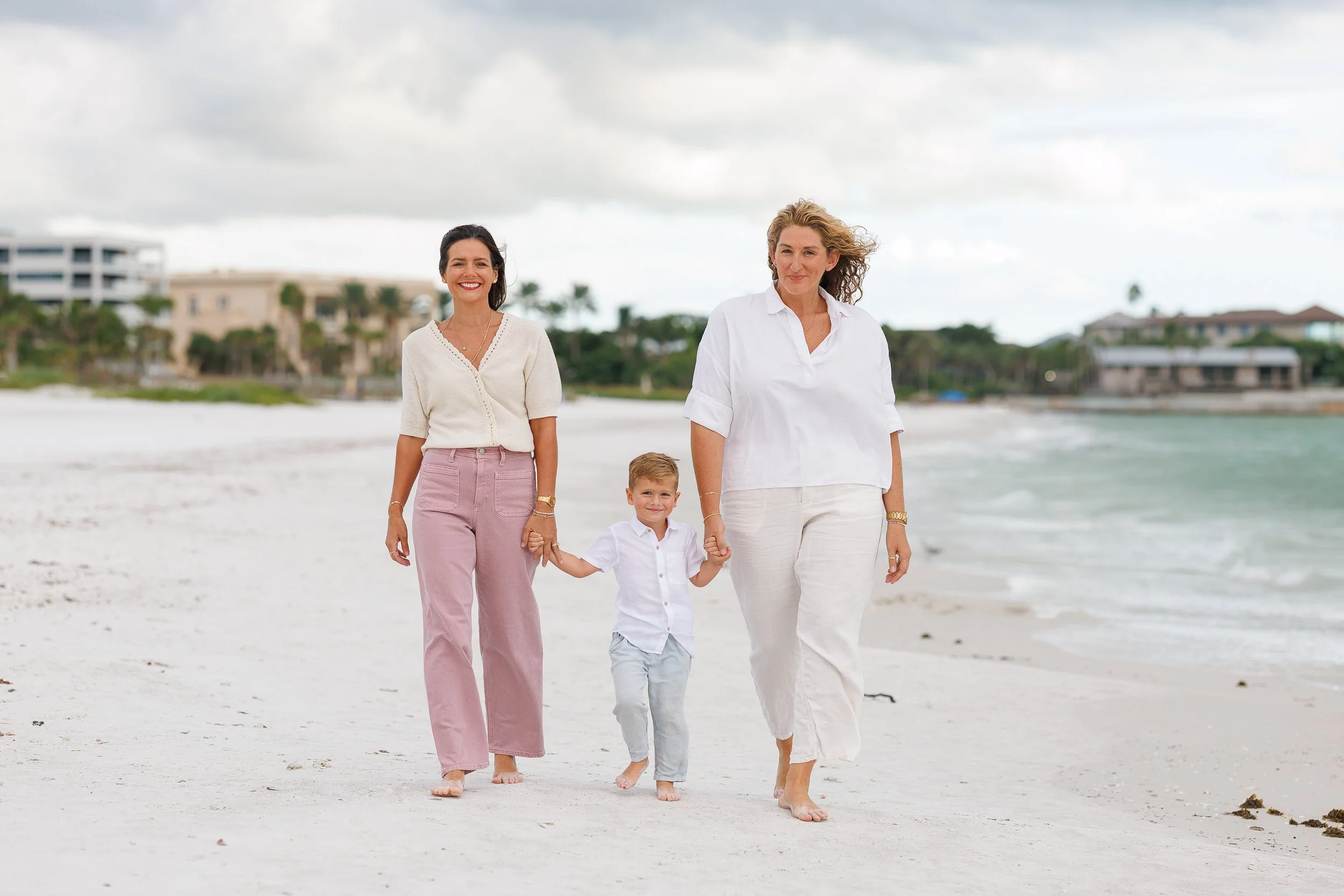 A family of three walking hand in hand on the beach at a Sarasota mini session