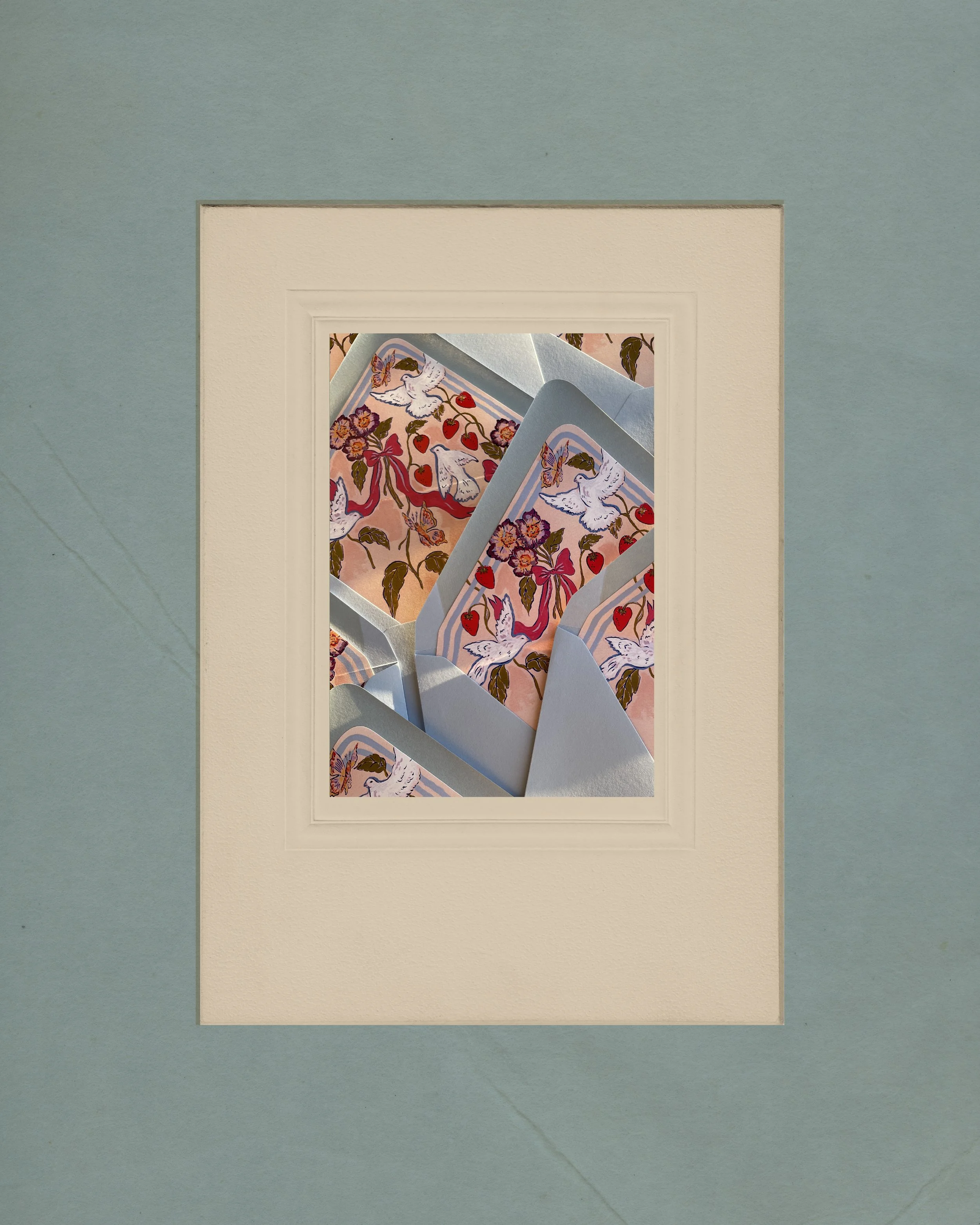 Close-up of several cards with a floral and swan pattern, arranged on a pastel surface.