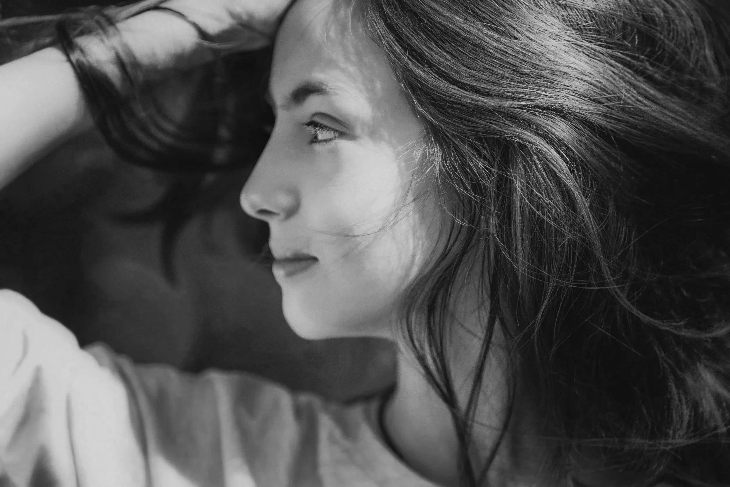 A black and white close-up photo of a woman with her head tilted and her eyes looking upward.