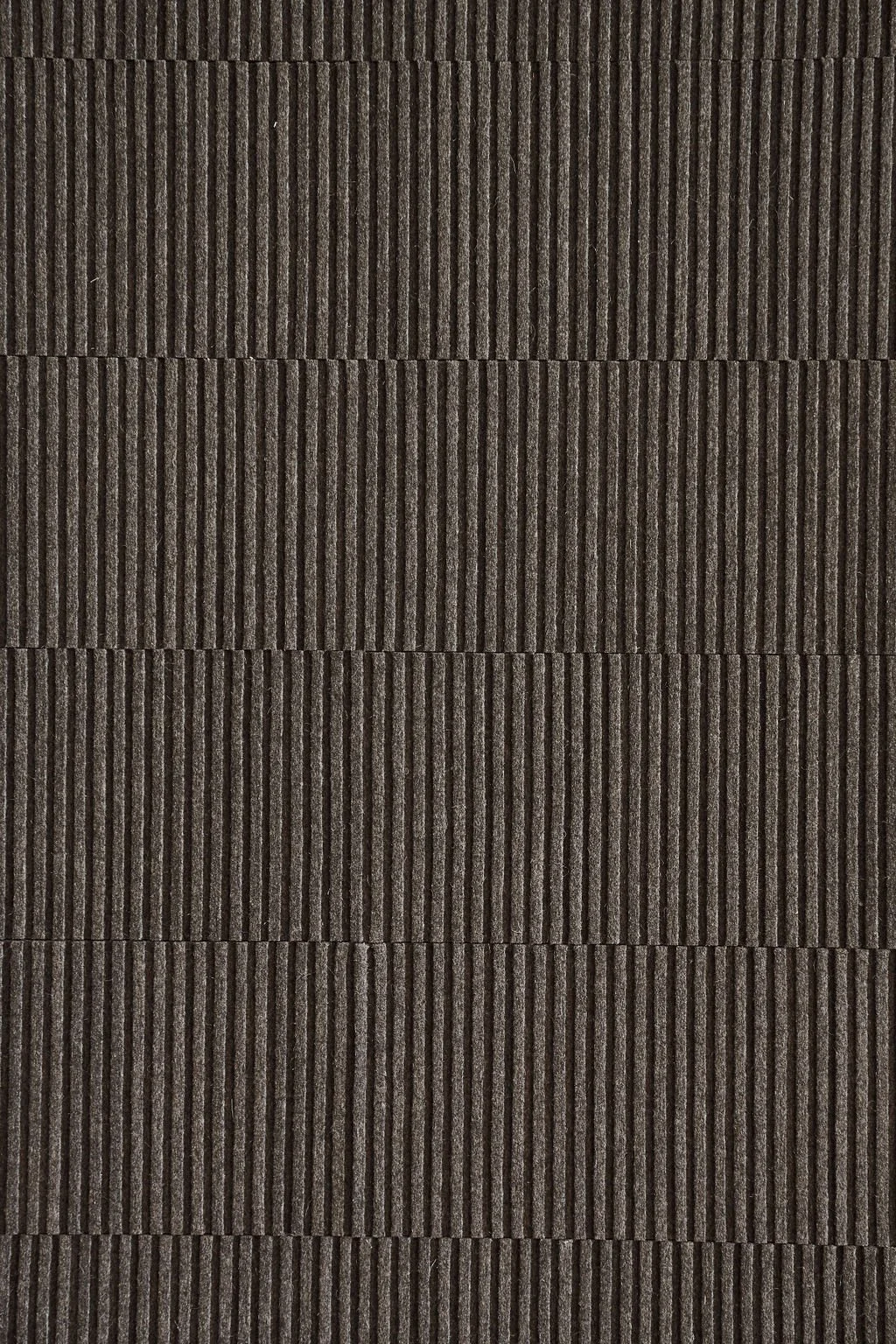 Close-up image of a section of dark brown, textured asphalt shingles with vertical ridges.