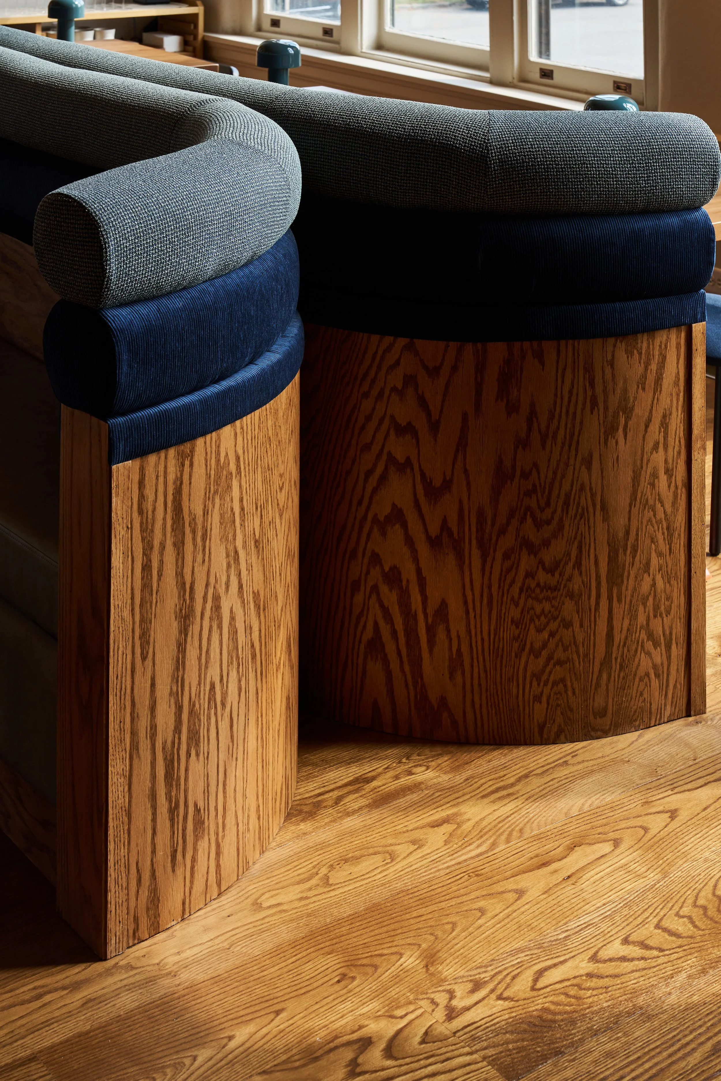 Close-up of a wooden counter with upholstered chairs, under natural light from a nearby window.