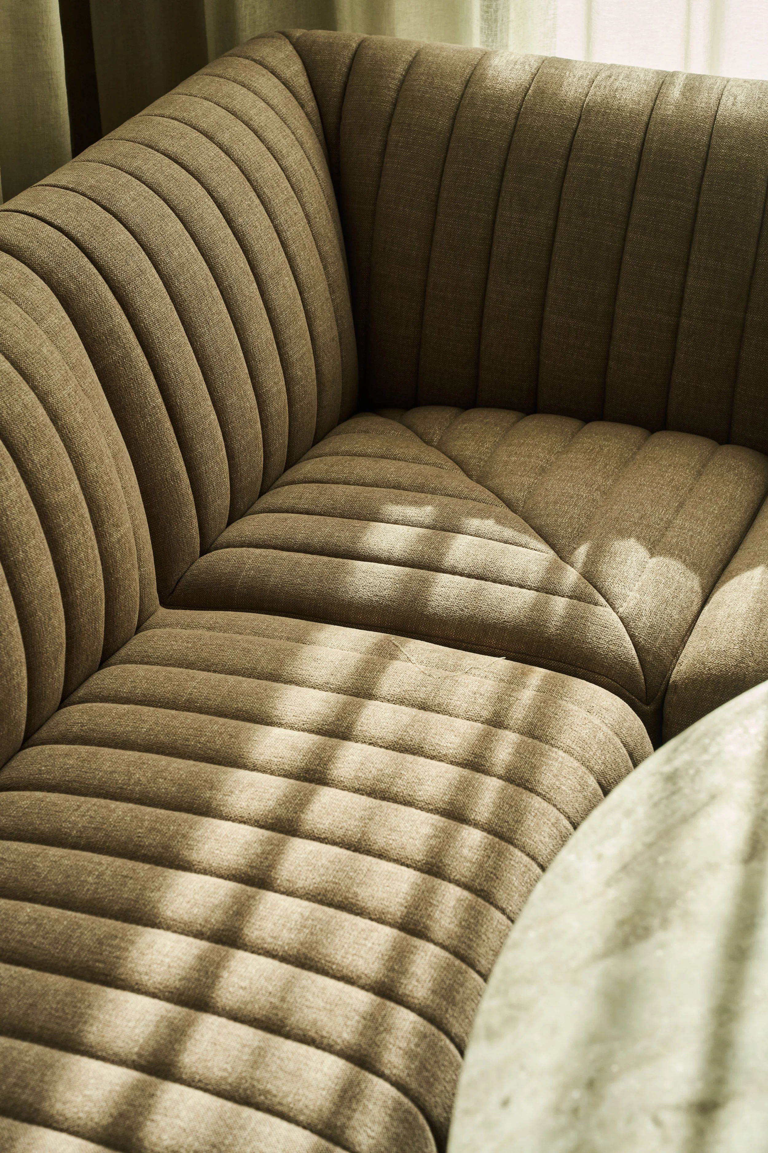 Close-up of beige upholstered furniture with ribbed design and cushion.
