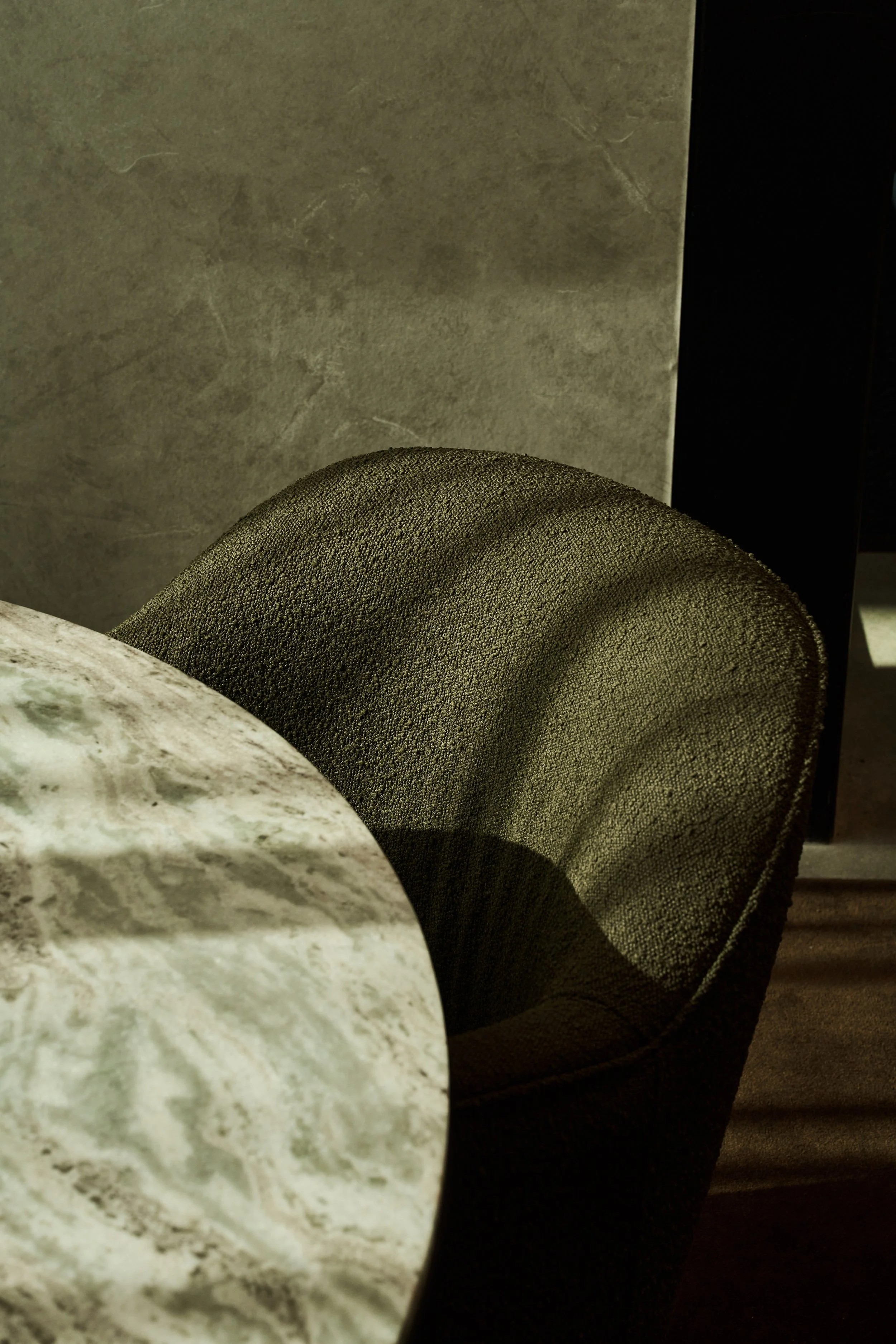 Close-up of a round, textured object next to a smooth, white marble surface, against a gray wall background.