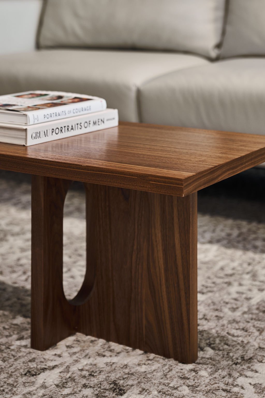 Close-up of a wooden coffee table with a couple of books on top, with a light-colored sofa in the background.