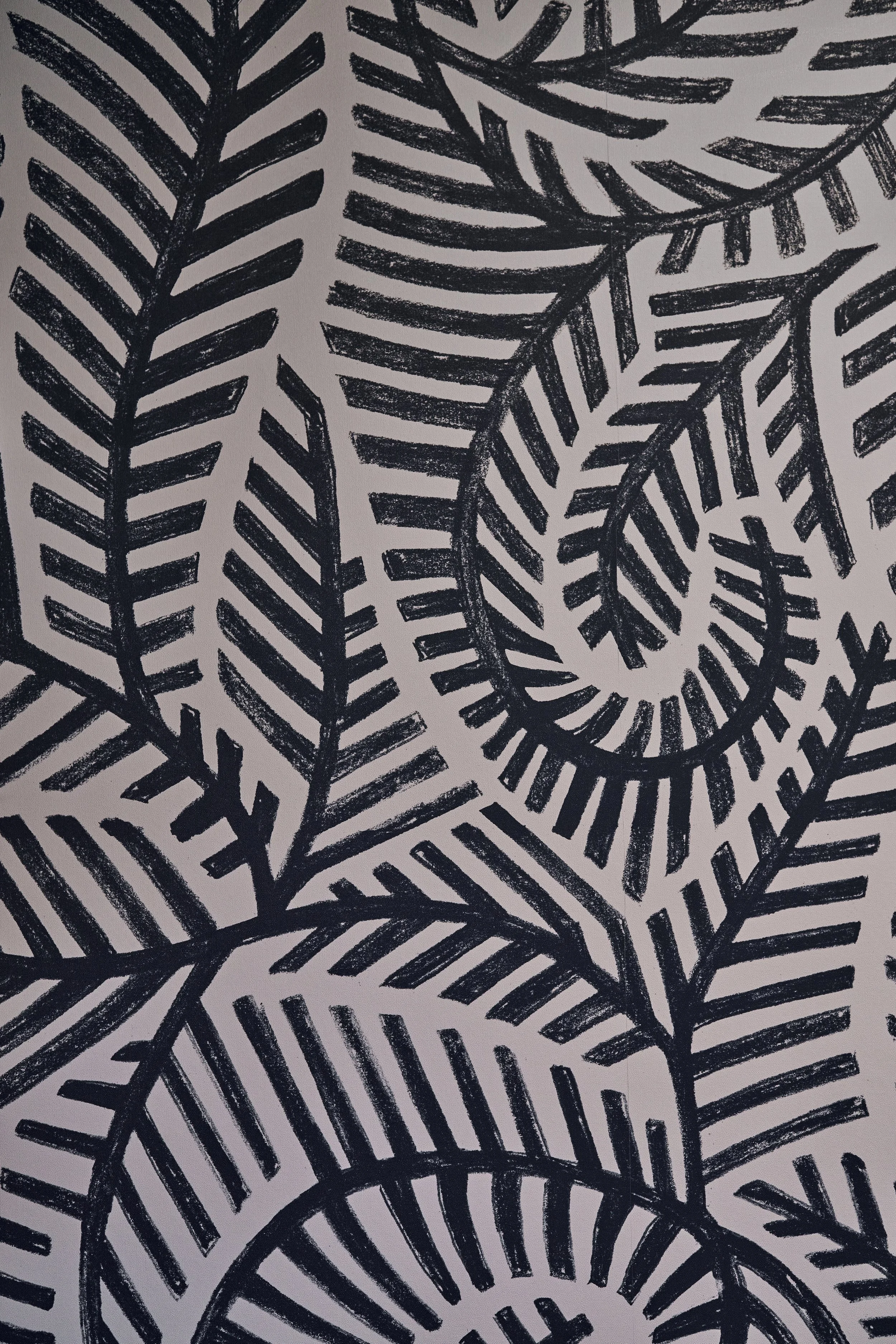 A black and white pattern of abstract fern or leaf shapes, with bold, textured lines on a light background.