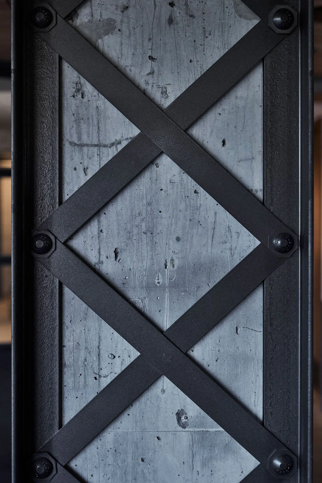 Close-up of a metal surface reinforced with black crisscrossing strips, secured with six screws, possibly part of a box or industrial equipment.