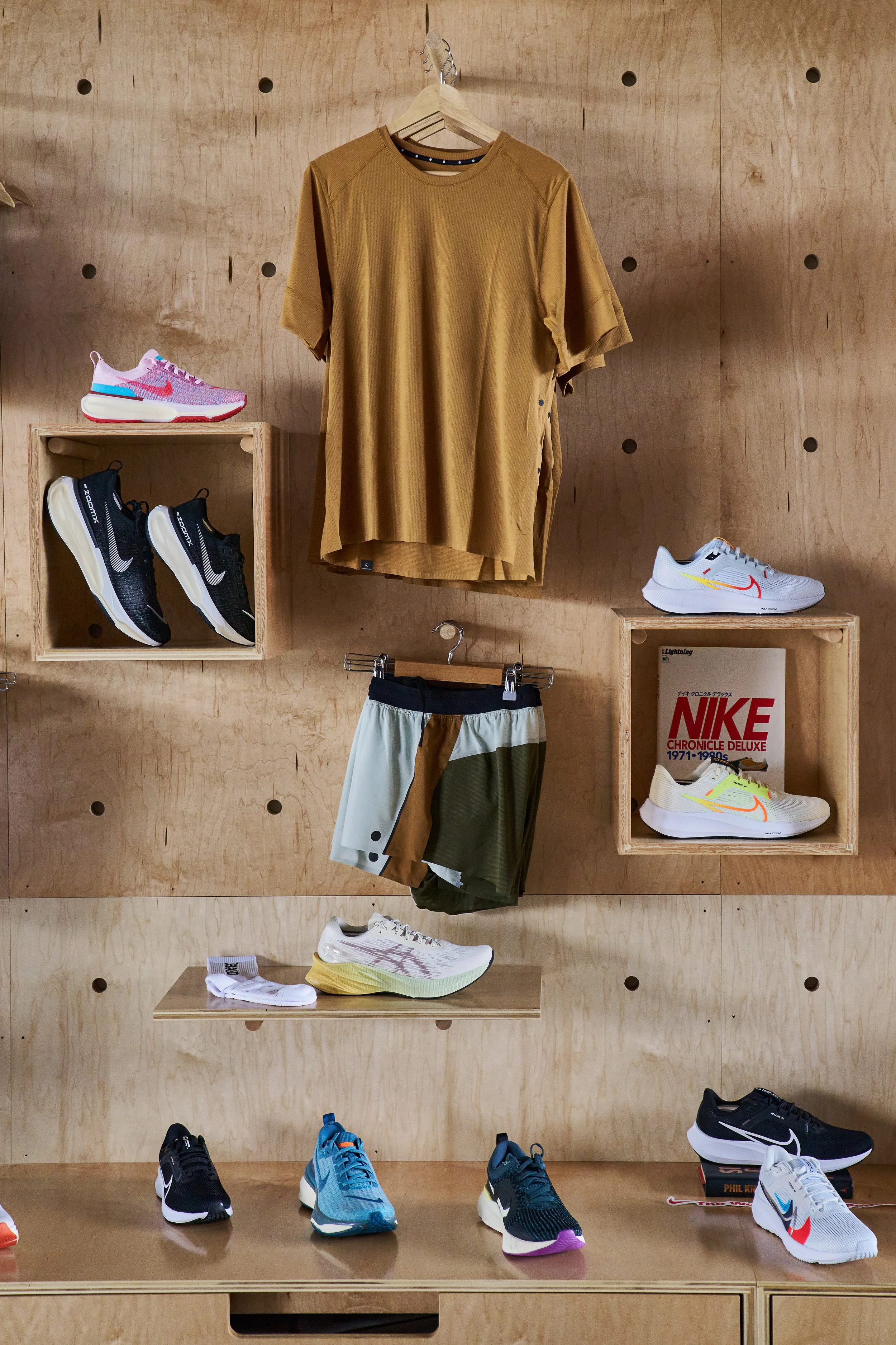 Display of athletic shoes and clothing on wooden shelves.