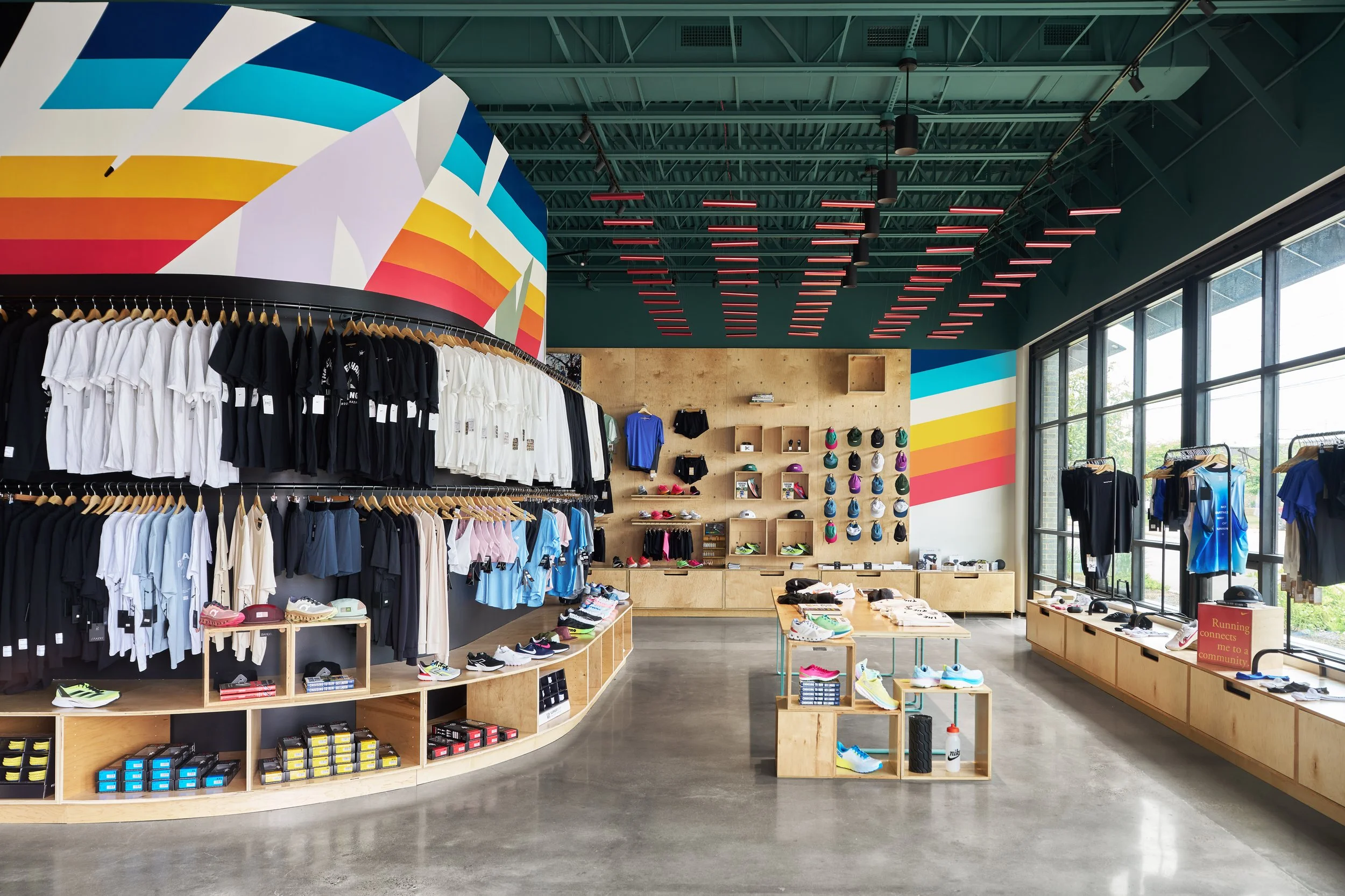 Inside a sports apparel and footwear store with colorful wall art, displaying t-shirts, shoes, and accessories.
