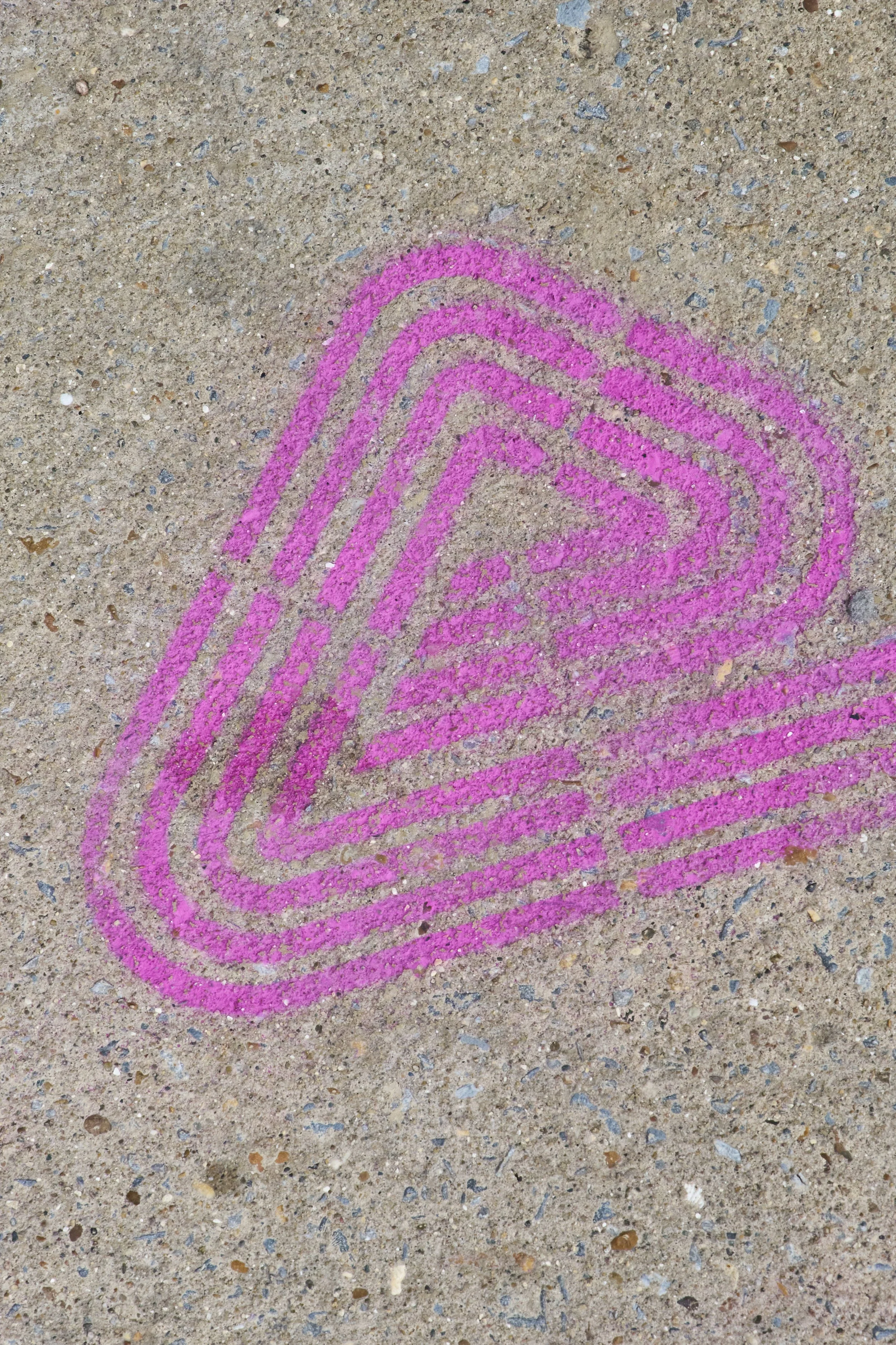 Pink chalk outline of a heart drawn on a concrete sidewalk.