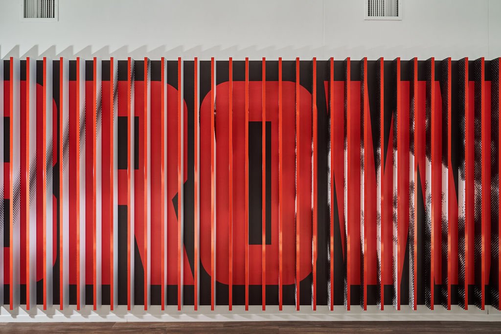 Red and black striped wall art with the word "LOVE" displayed behind vertical red and black slats.