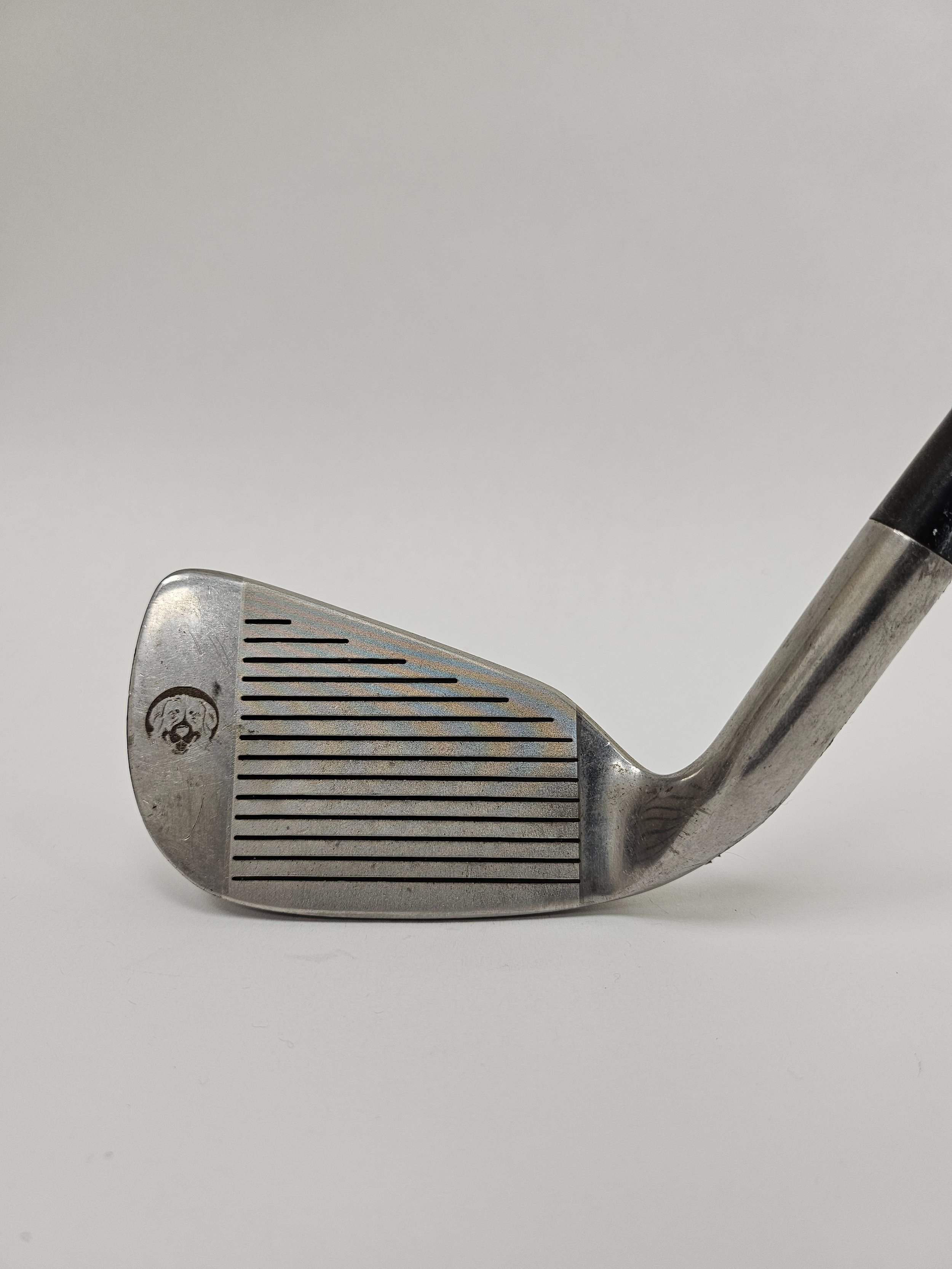 Close-up of a laser resurfaced golf wedge club showing the clubface with grooves and a logo of a dog's face.