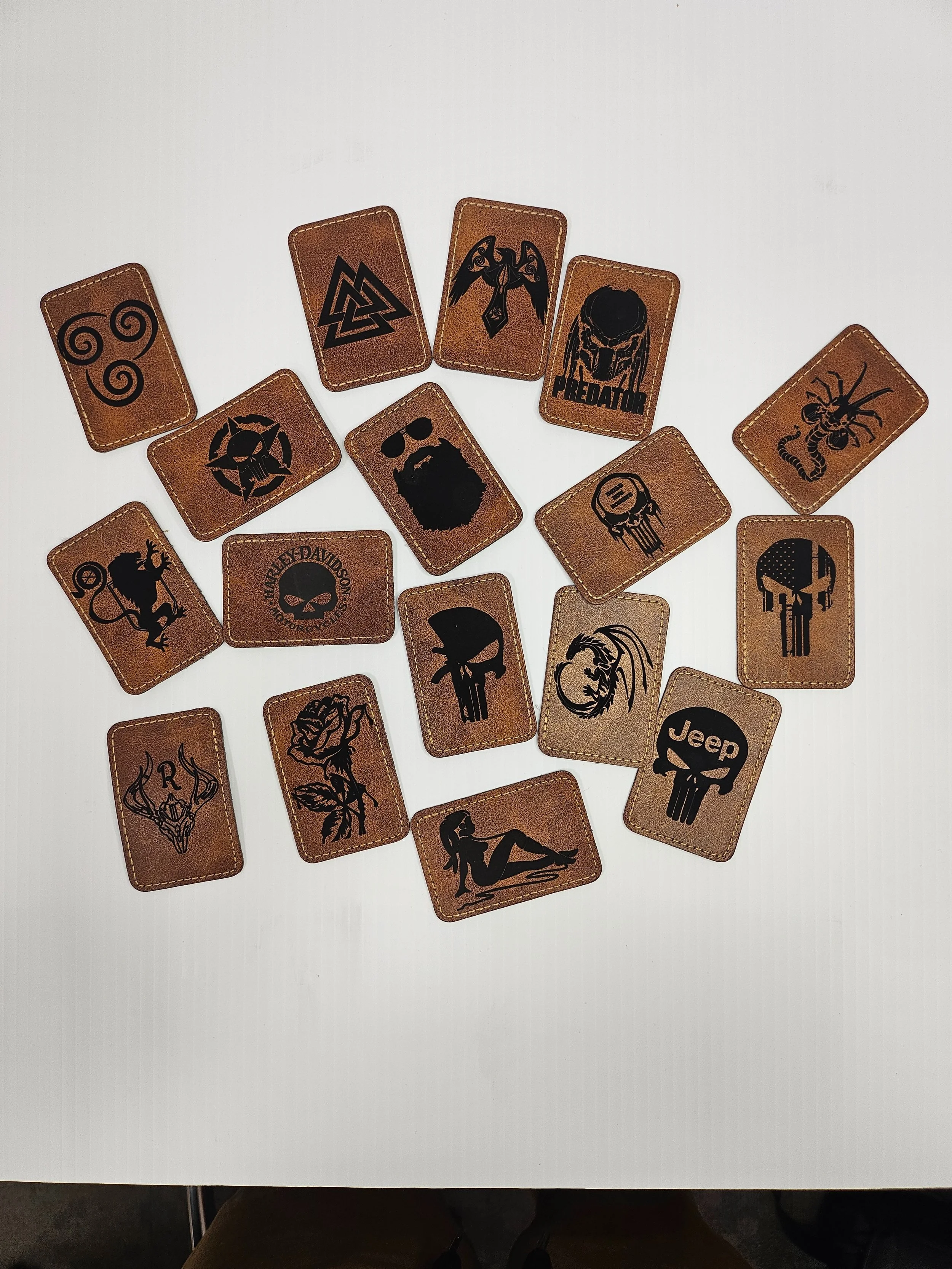 Collection of iron on leather patches, spread out on a white surface.