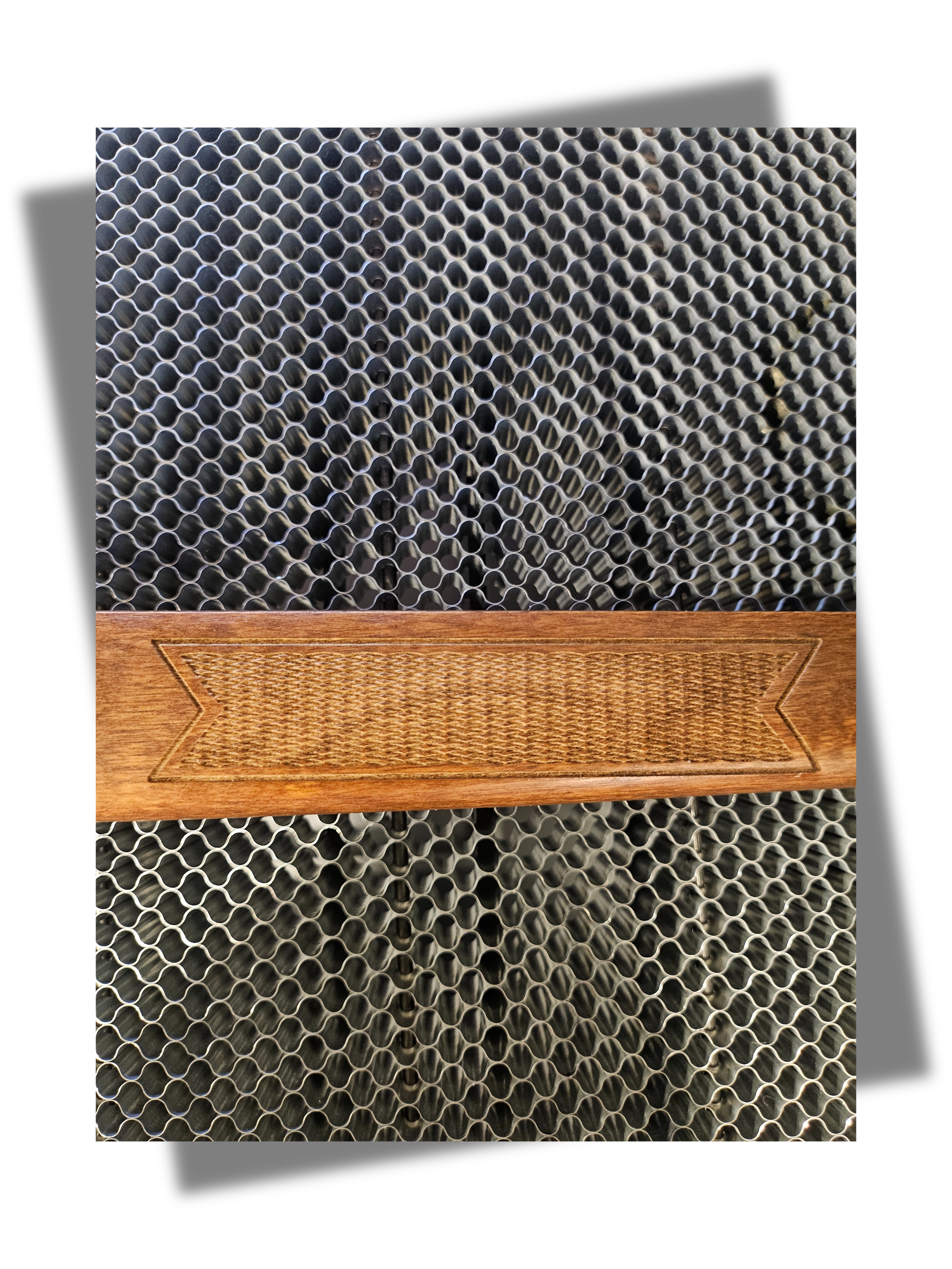 Close-up of a wooden rifle stock with a textured grip, resting on a metallic honeycomb-patterned surface.