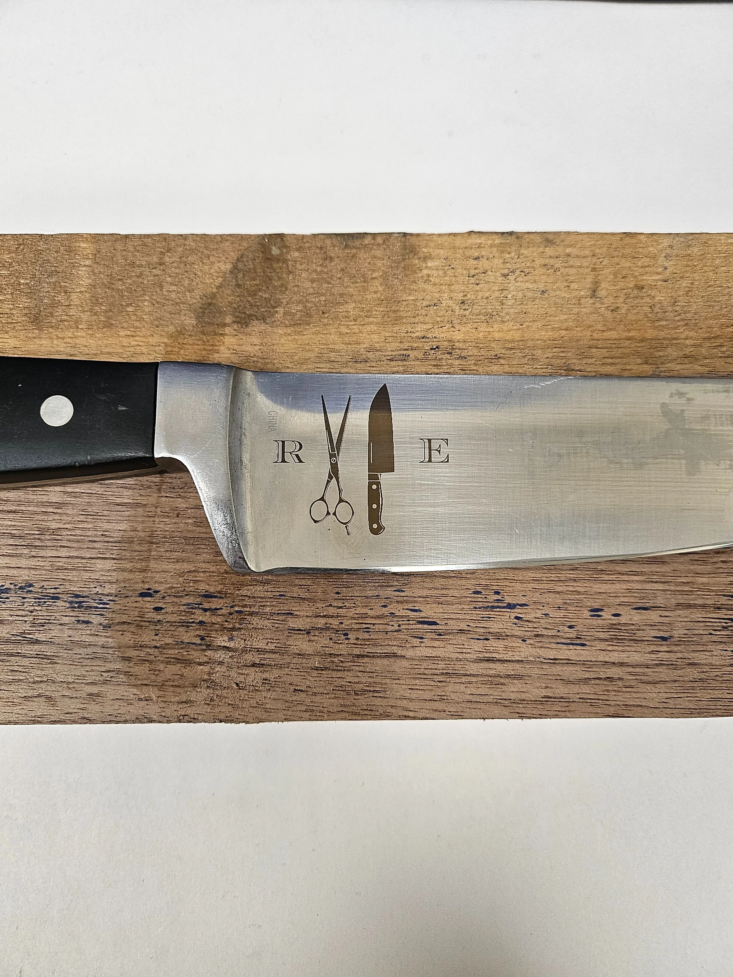 A kitchen knife with the Refined Edge company logo engraved on the blade.
