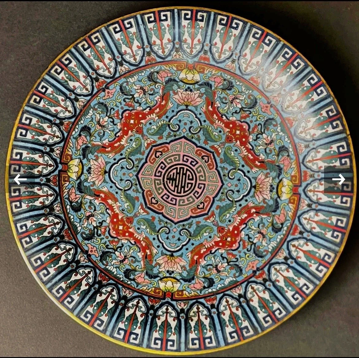 Decorative round plate with traditional Asian motifs including dragons and floral patterns in red, blue, pink, green, and black colors.
