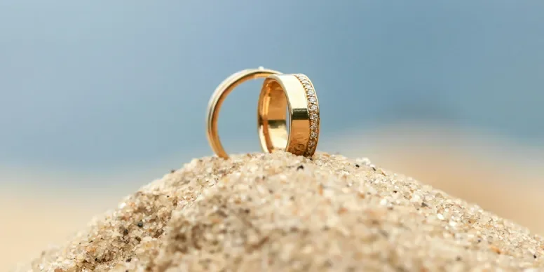 two wedding rings sitting on beach sand
