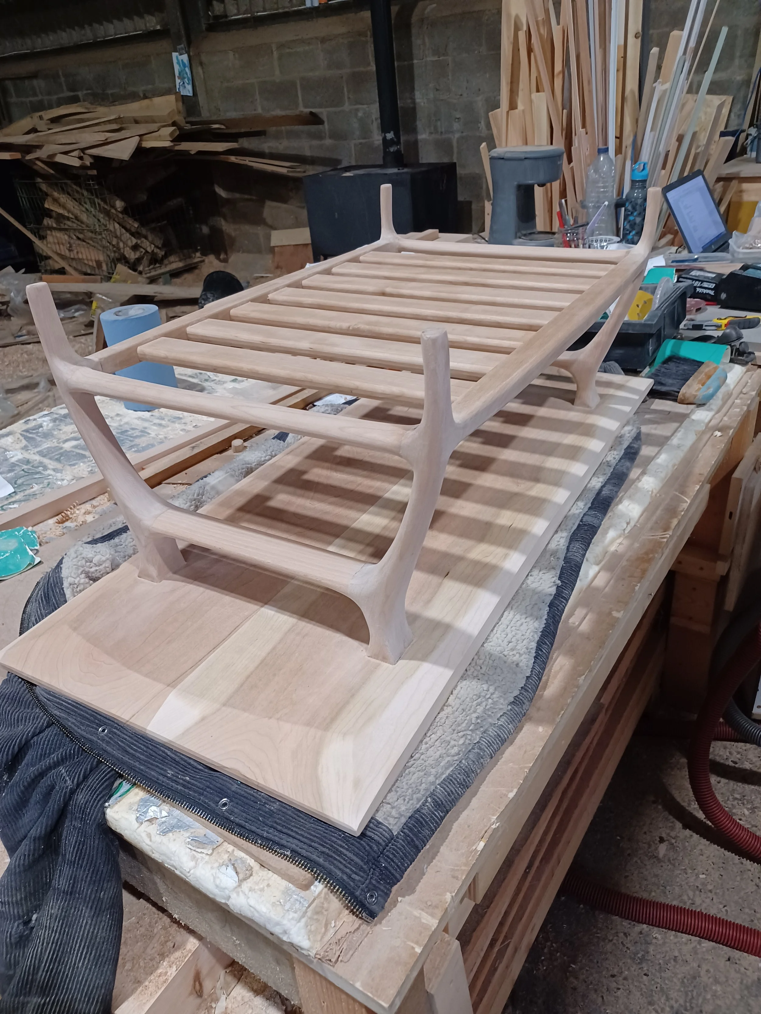 Wooden shelf or rack frame in woodworking shop with tools and wood pieces in the background.