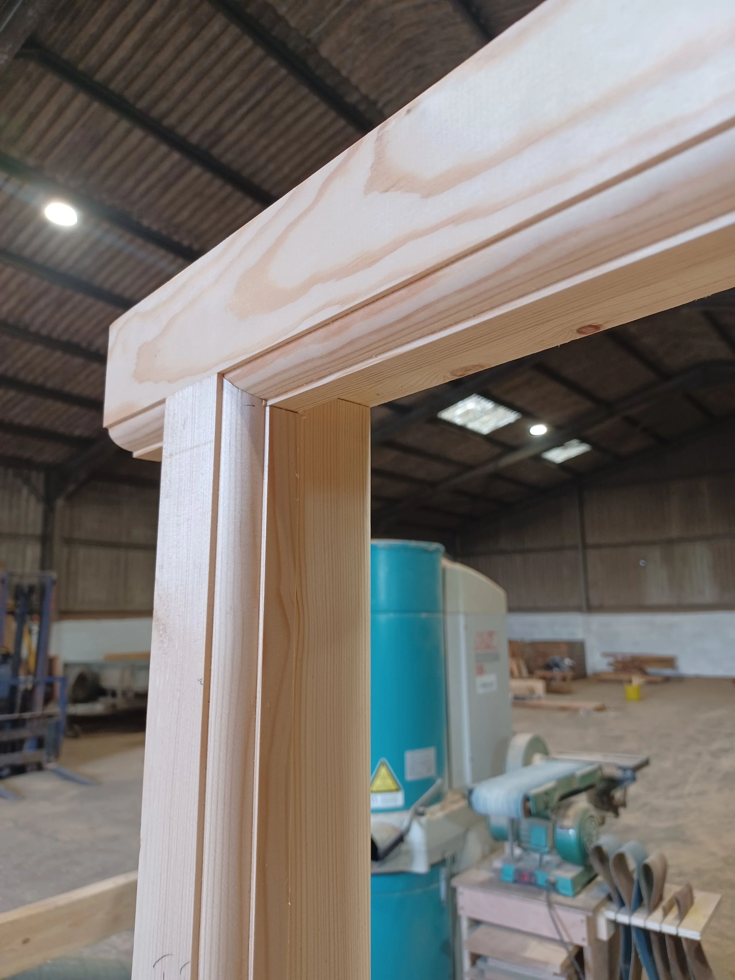 Close-up of a wooden doorway frame under construction in a woodworking workshop.