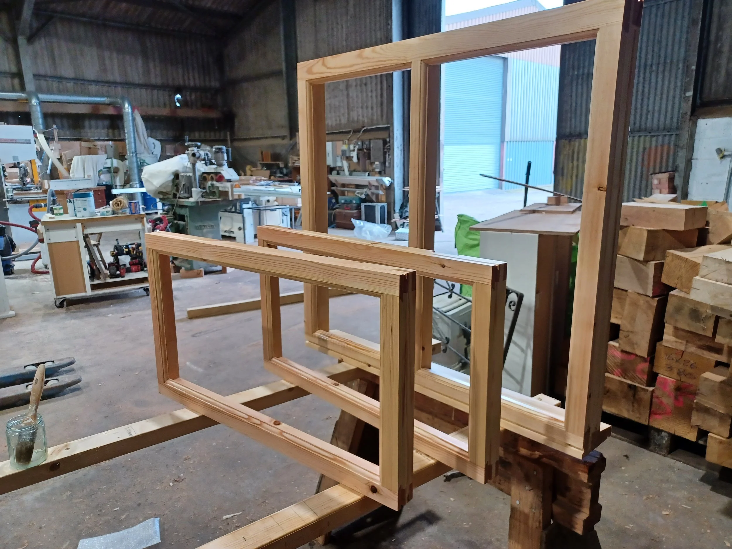Wooden window frame in a workshop with various tools and materials in the background.
