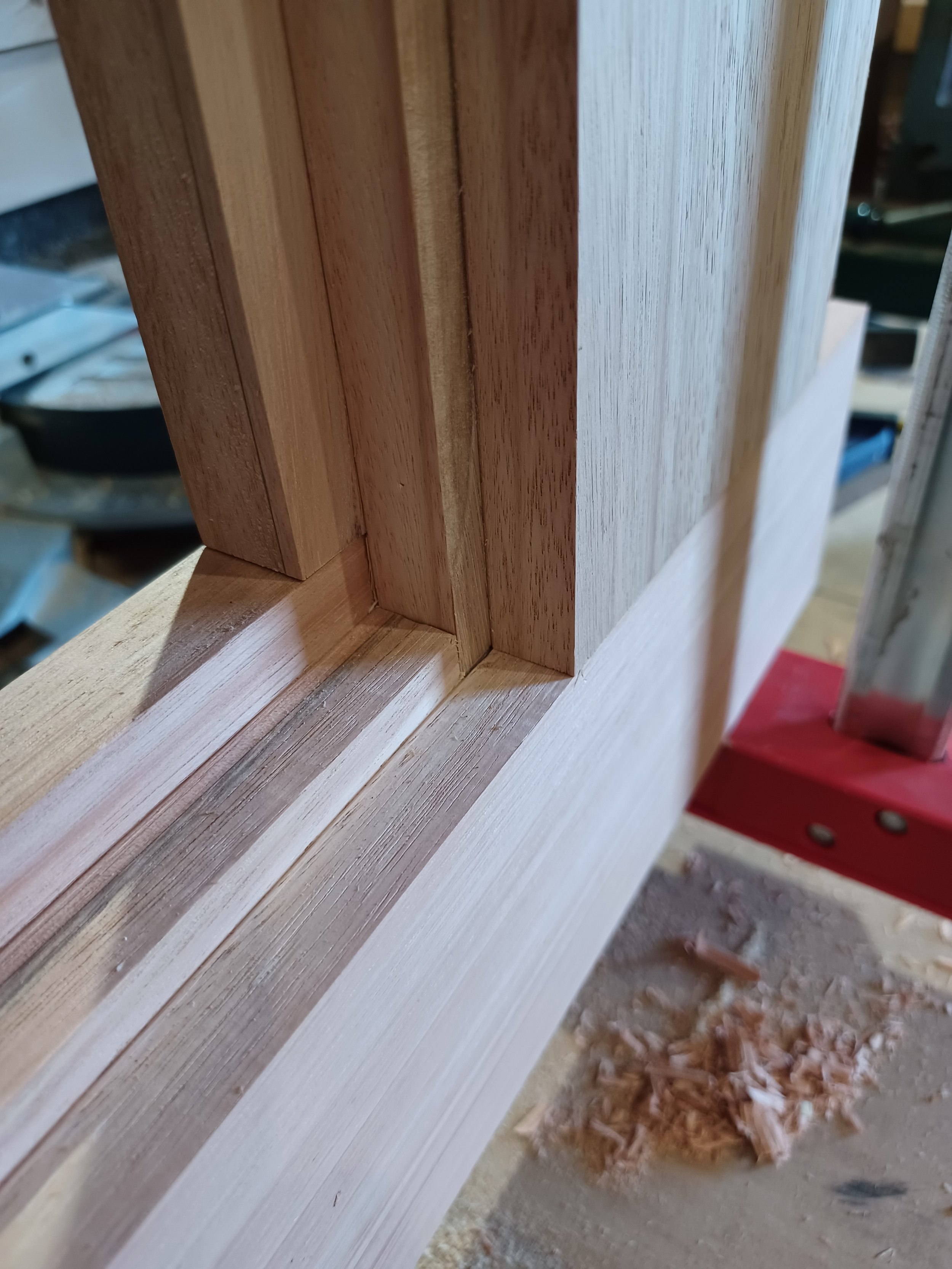 Close-up of a woodworking project with wooden joints and a red ladder in a workshop.