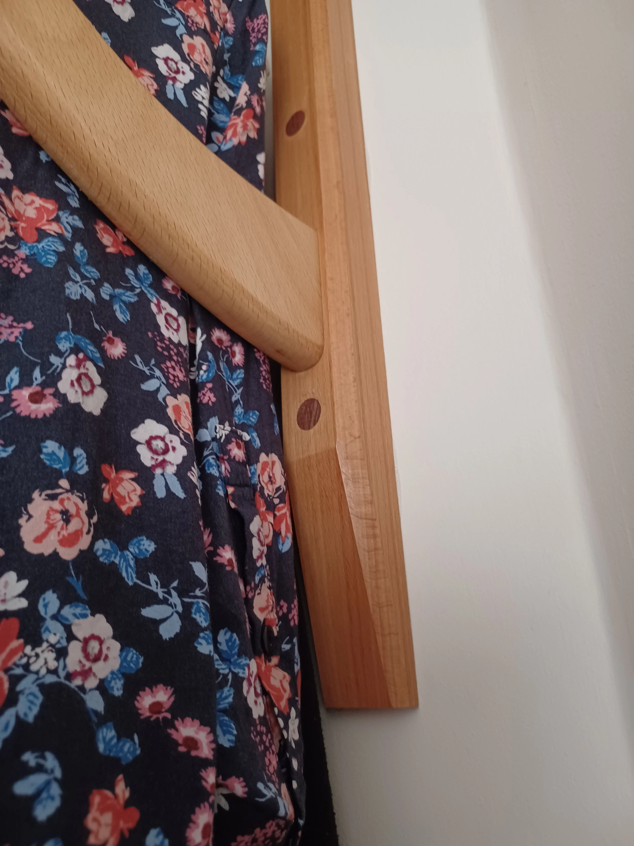 Close-up of a wooden bed frame with a floral bedspread.