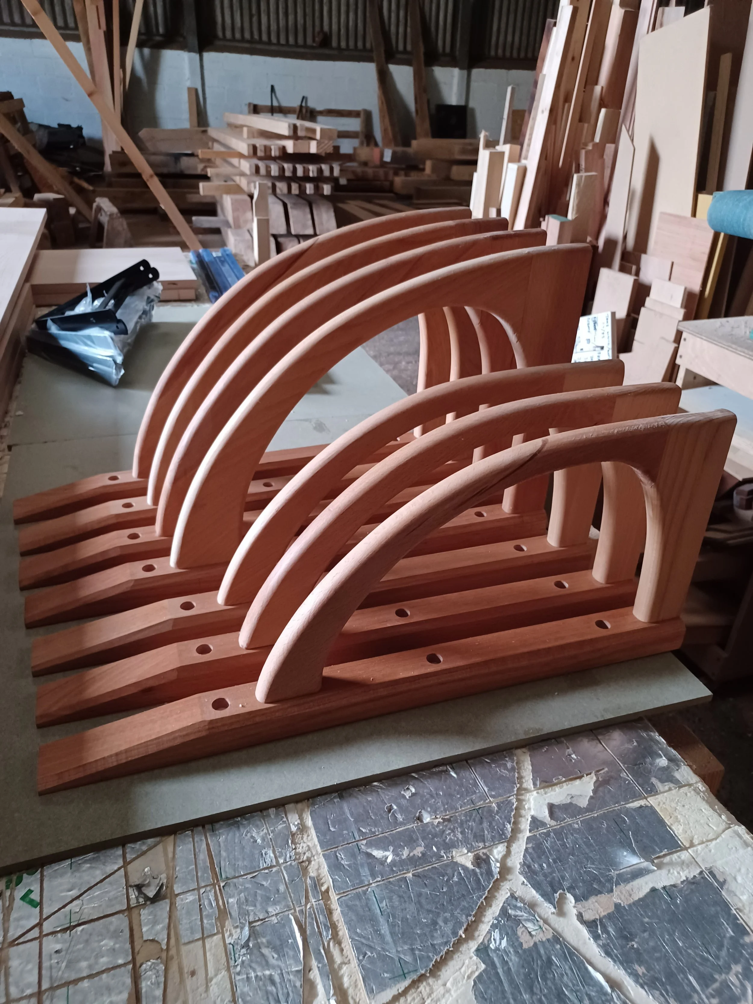 Six wooden bookends with a curved design arranged on a workbench in a woodworking shop.