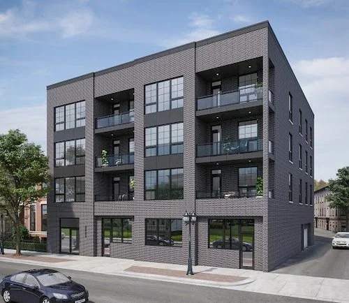 Modern four-story apartment building with multiple balconies, large windows, and a dark gray brick exterior, located on a city street with parked cars and trees.
