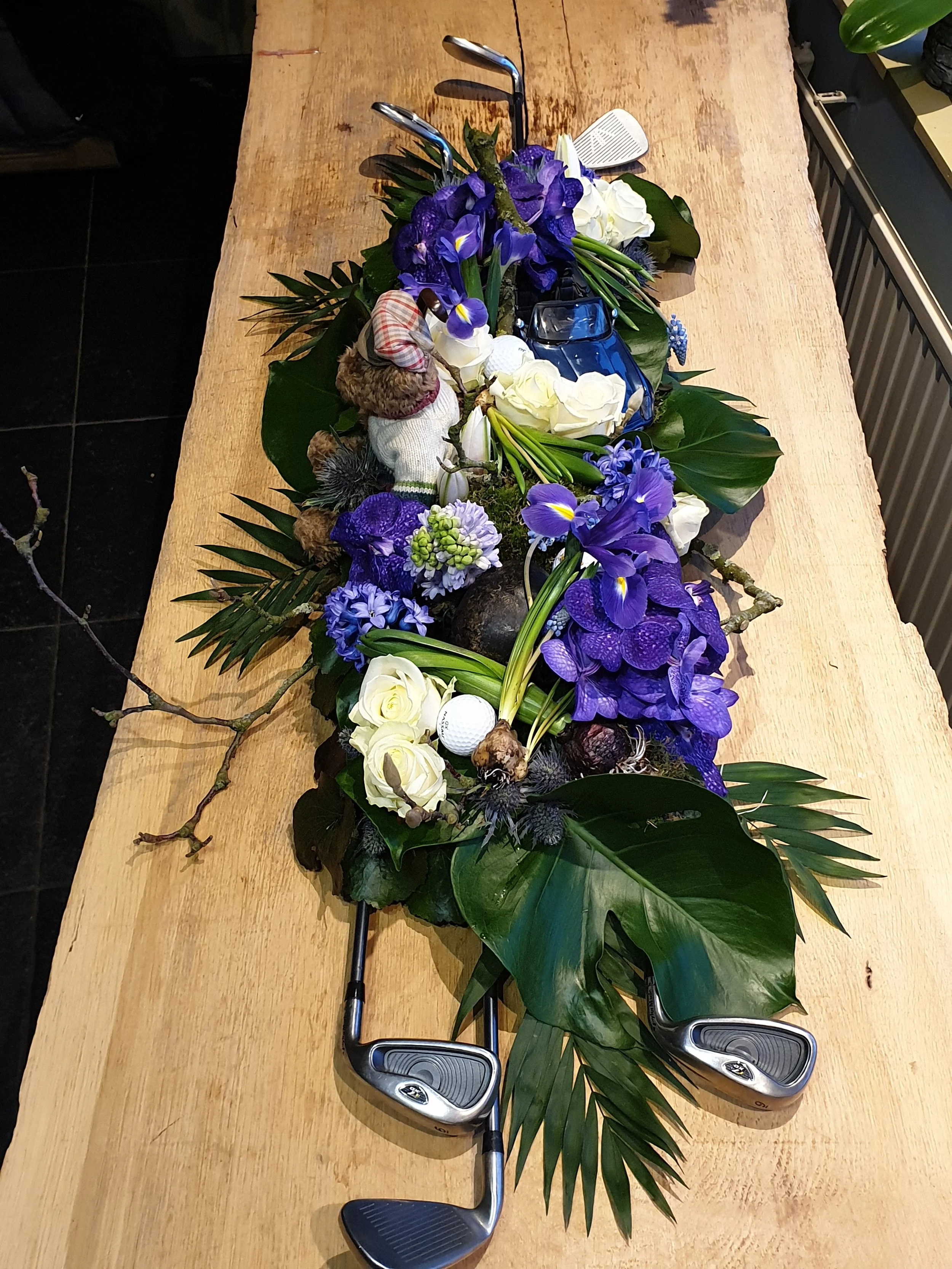 Golfclubs en bloemen op een houten tafel.