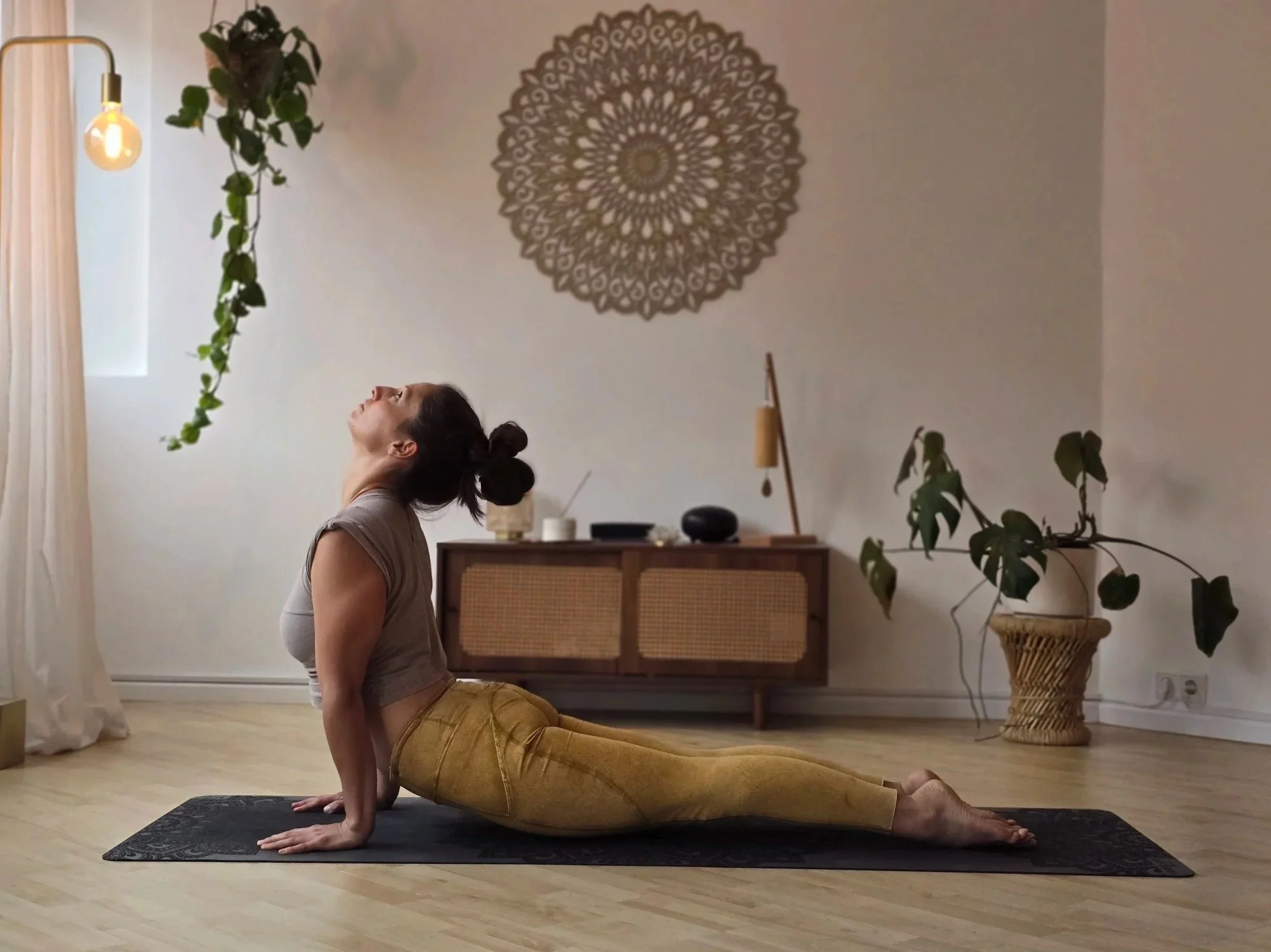 Eine Frau macht Yoga in einem stilvollen, minimalistischen Raum mit Pflanzen und dekorativen Elementen.