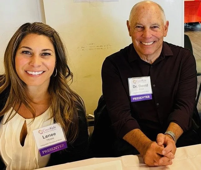 A woman and a man sitting at a table, both smiling at the camera. The woman has long, wavy hair and is wearing a white top with a name tag that says 'Lenee Horne' and 'PRESENTER'. The man is bald, wearing a black shirt, and has a name tag that says 'Dr. David' and 'PRESENTER'.