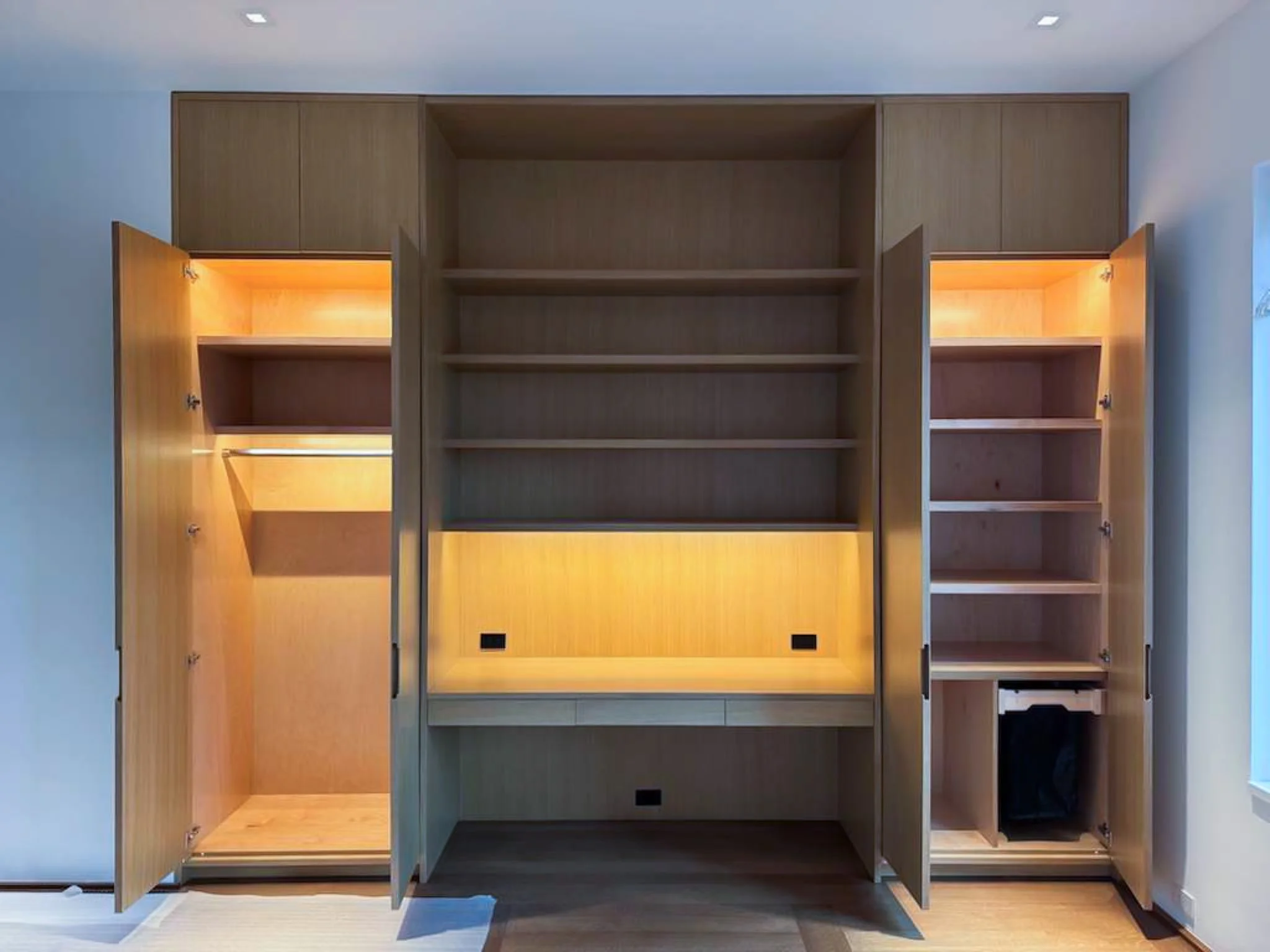 Modern wall unit with open shelving and cabinets, featuring built-in lighting and power outlets.