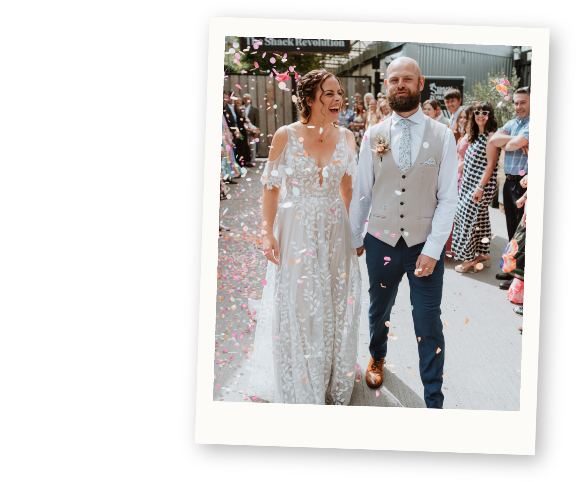 Bride and groom smiling while walking through colourful confetti after their wedding ceremony.