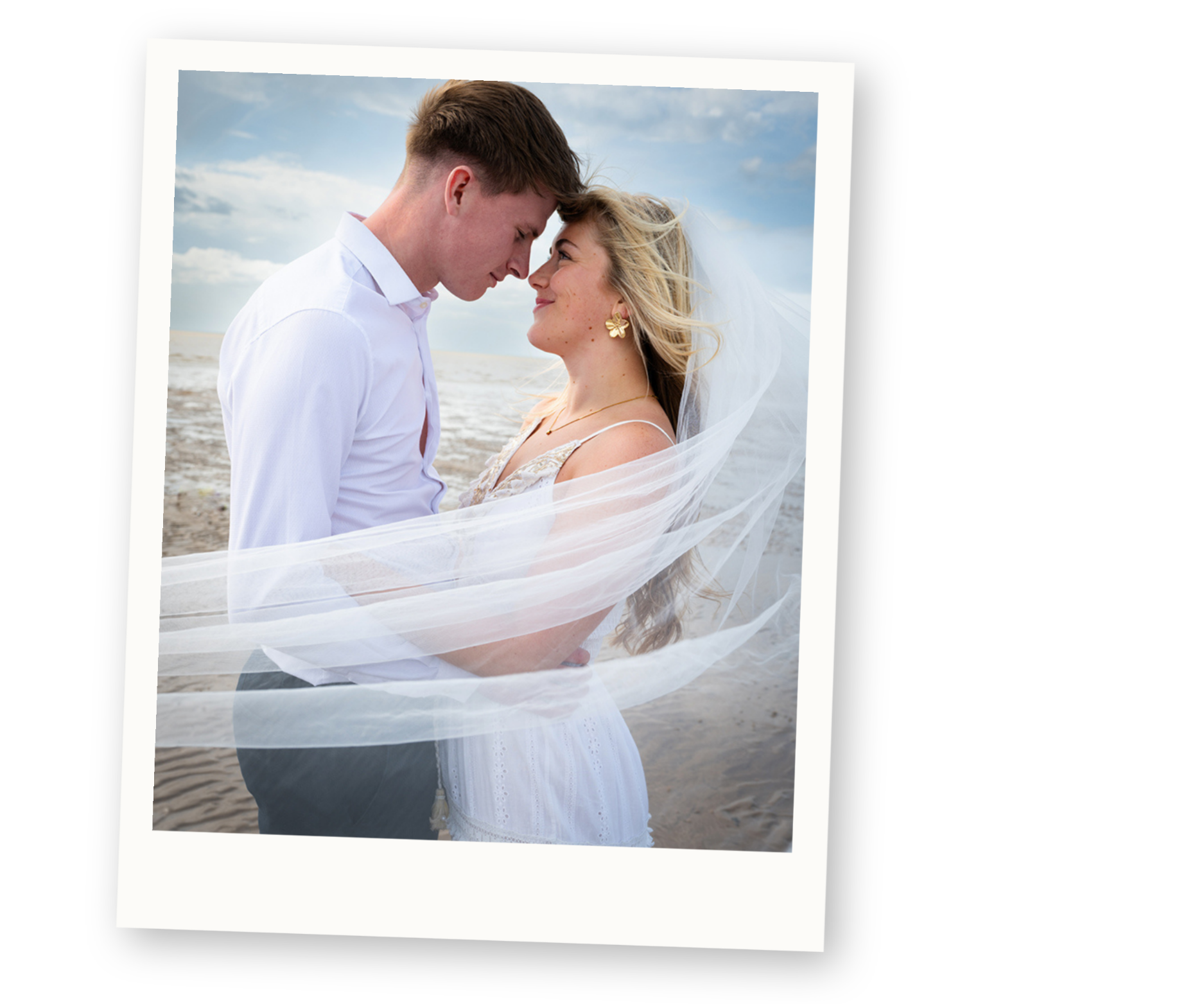 Relaxed beach wedding portrait of a bride and groom embracing at sunset.