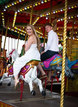 Couple enjoying a fun fair carousel during a relaxed engagement style photo shoot.