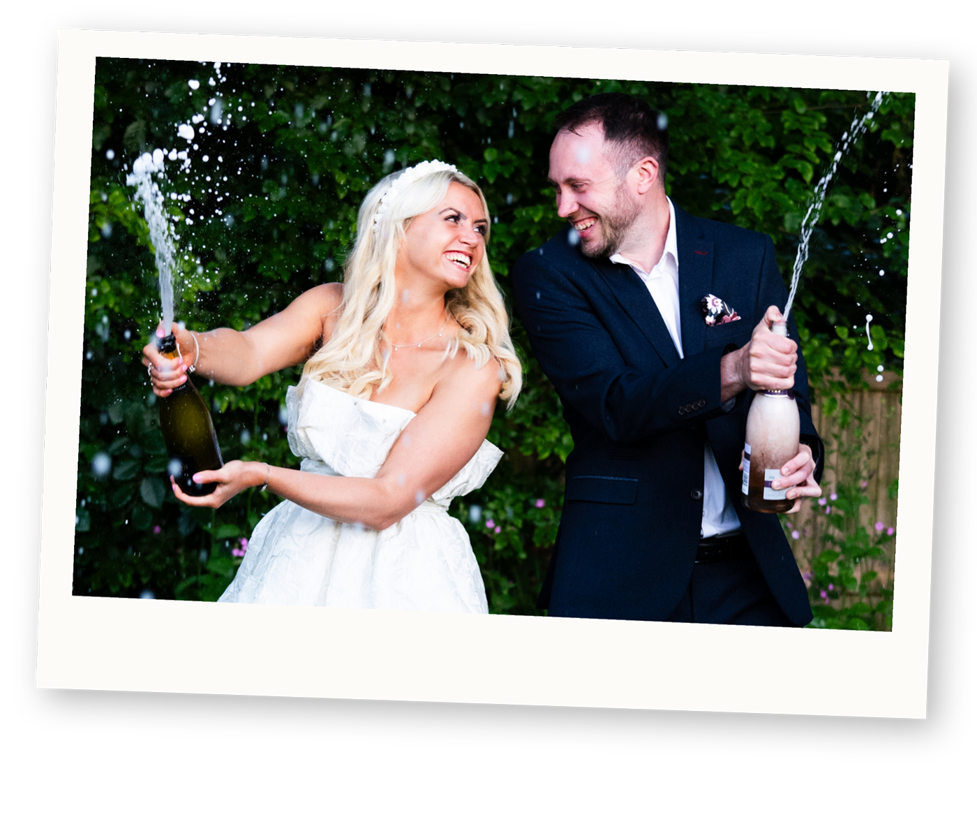 Couple spraying champagne during a fun engagement photoshoot.