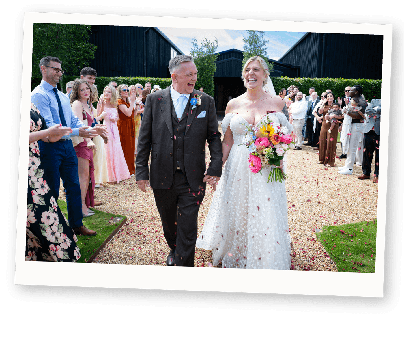 A joyful couple walking through confetti after their wedding ceremony, photographed by alternative wedding photographer Kiss Photo in Banbury..