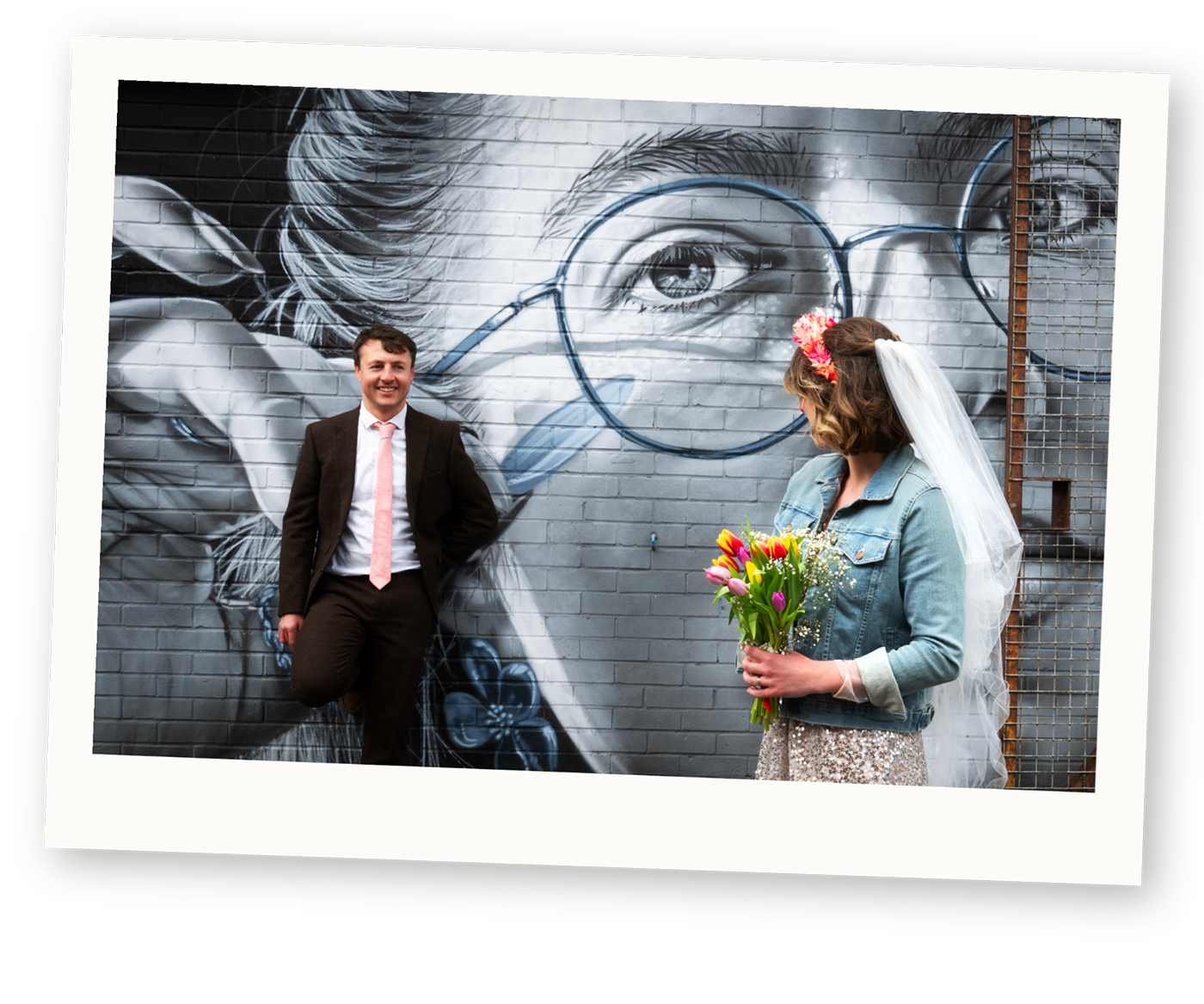 Couple standing beside colourful street art during an alternative engagement shoot.