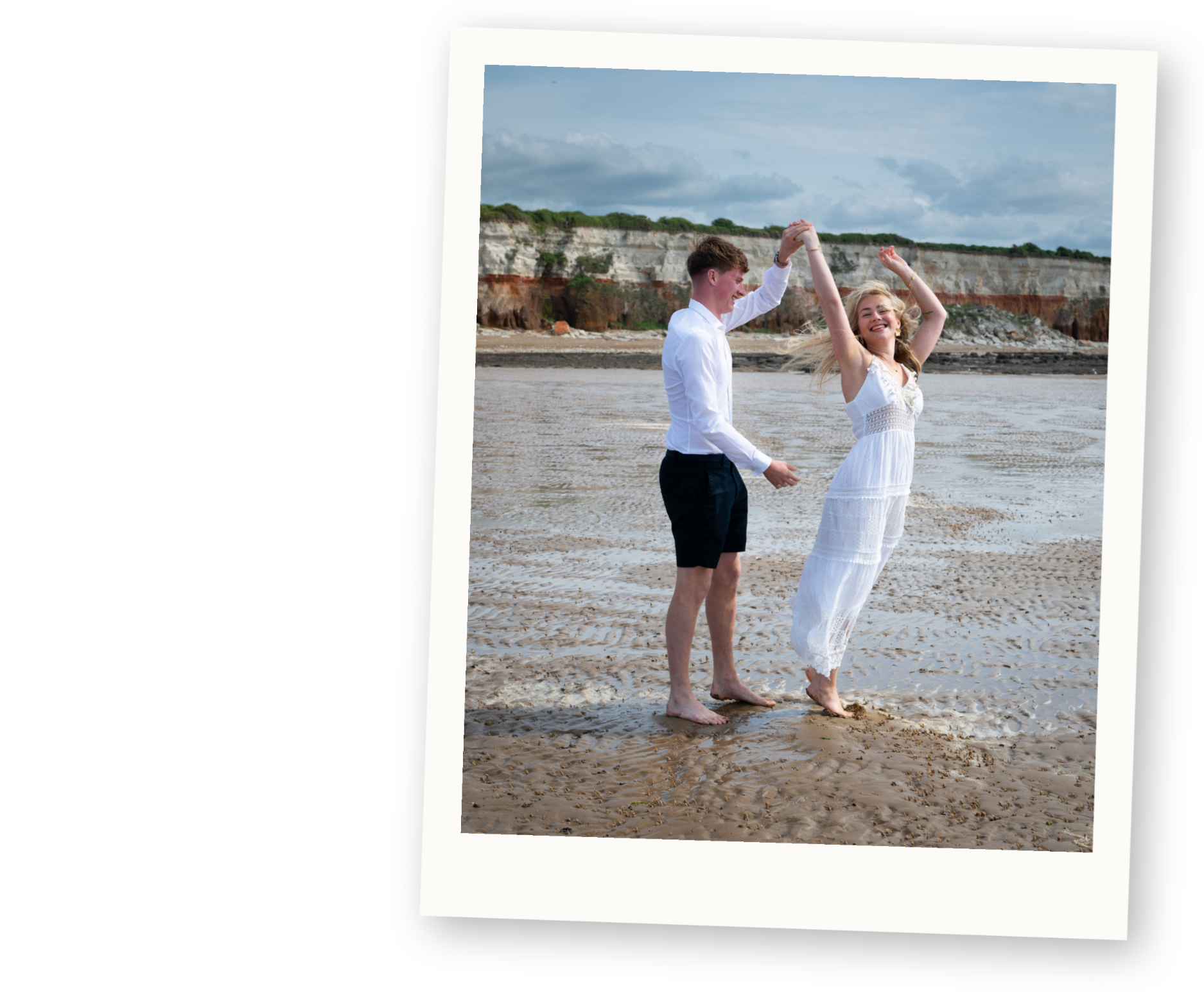 Couple dancing together on the beach during a relaxed engagement style photo shoot.