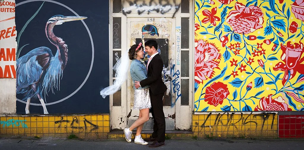 Alternative wedding portrait in front of colourful street art in an urban location.