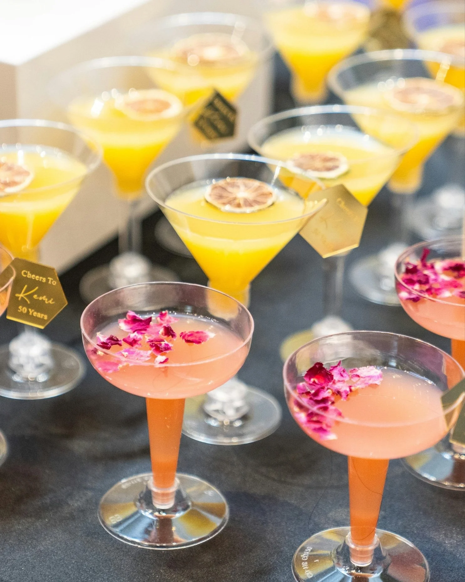 Elegant signature cocktails with rose petal garnishes and citrus martinis displayed at a special event